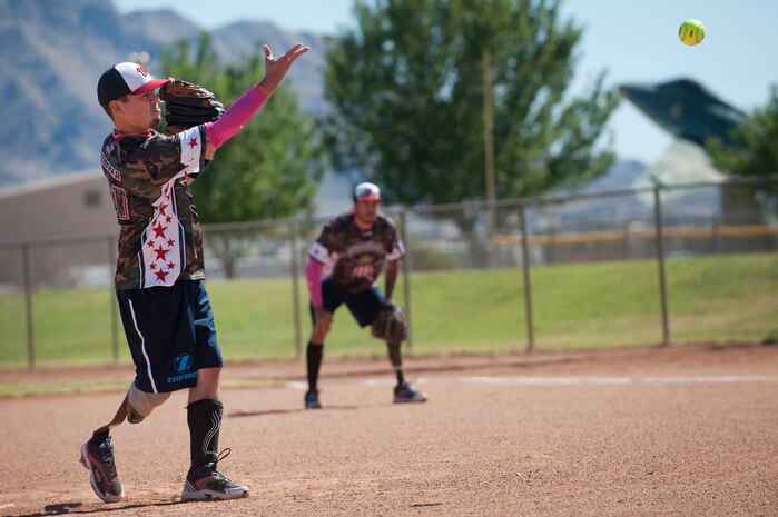 Michael Dreyer, Wounded Warrior Amputee Softball Team member, pitches a ball as Michael Gallardo, WWAST member, waits to react at first base during a Wounded Warrior softball game at the baseball field at Freedom Park Oct. 5, 2013, at Nellis Air Force Base, Nev. The Wounded Warrior Amputee Softball Team played against Airmen from Nellis and Creech AFBs during a double header. The Nellis and Creech AFBs’ softball team defeated the WWAST during the double header 15-10 and 25-11.  (U.S. Air Force photo by Staff Sgt. Christopher Hubenthal)