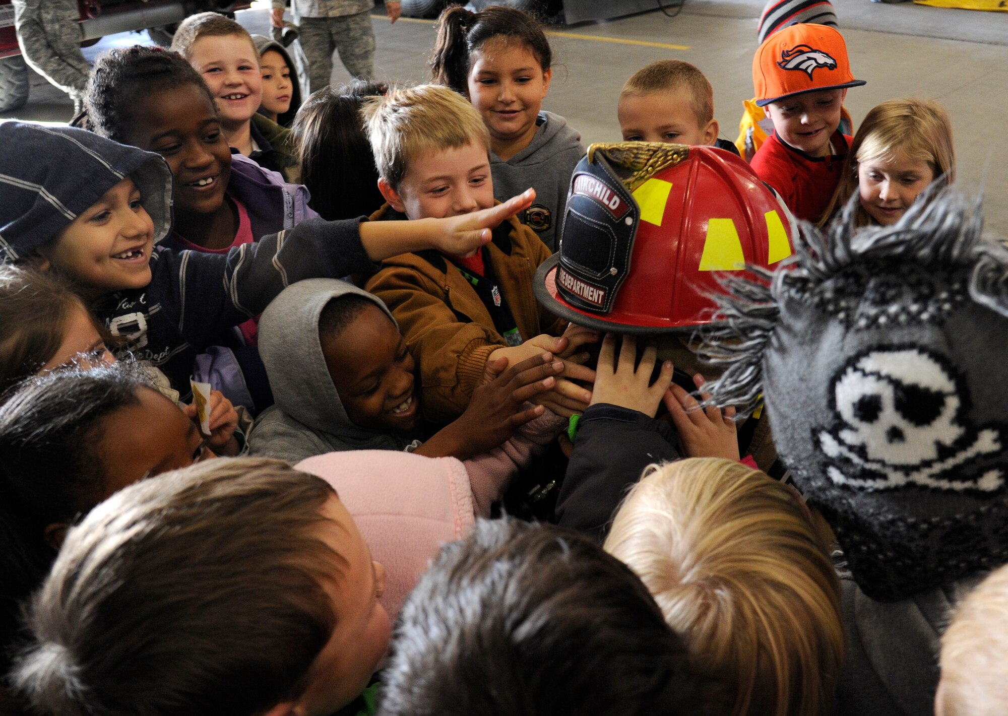 A group of students from Michael Anderson elementary closely inspect a fire fighters gear in the fire department at Fairchild Air Force Base, Wash., Oct. 7, 2013. The fire department wants children to be familiar with how fire fighters look in their personal protection equipment, so they are not afraid of them if encountered in an emergency situation. (U.S. Air Force photo by Airman 1st Class Ryan Zeski/Released)