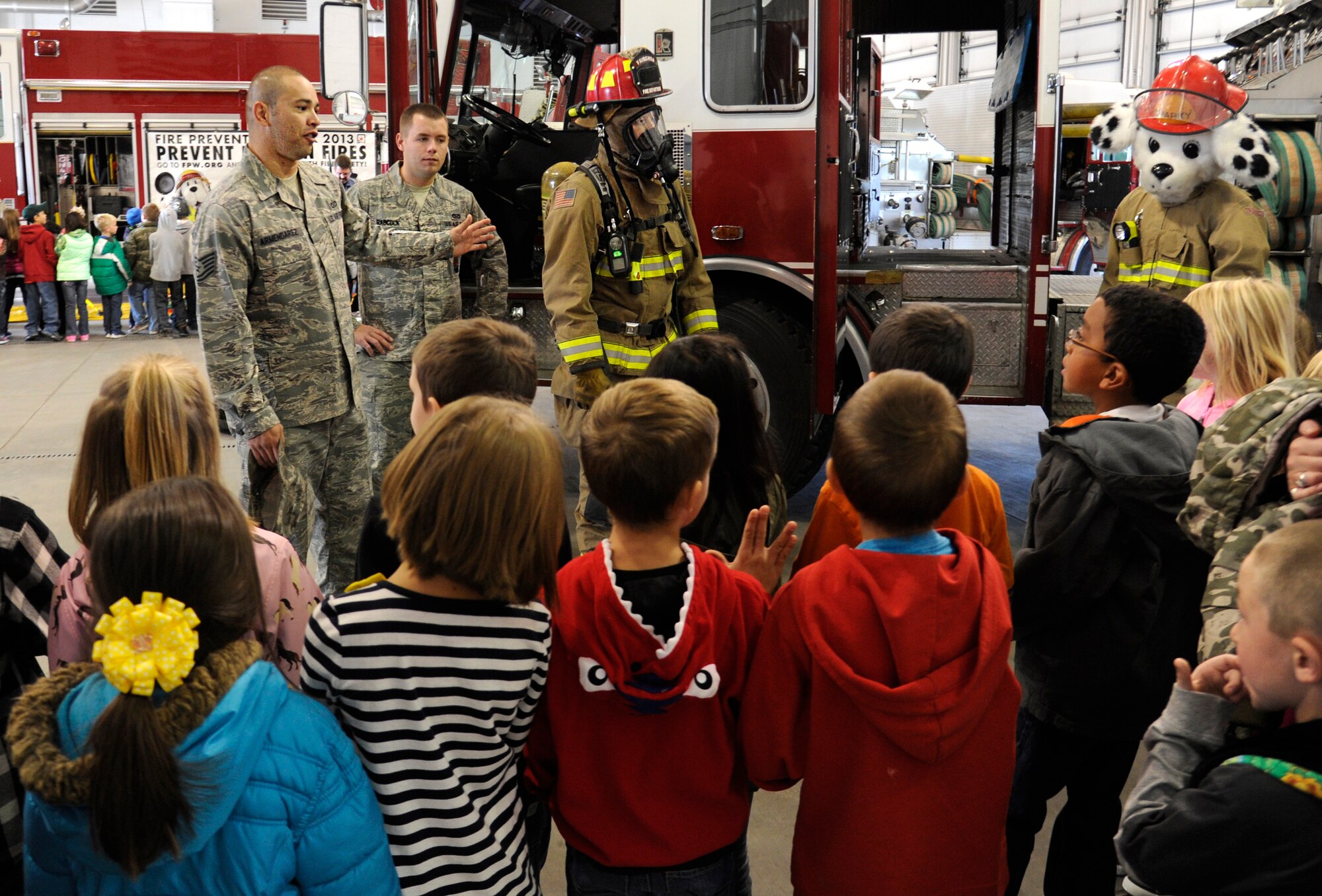 Tech. Sgt. Joel Armendarez and Senior Airman Christopher Babcock, 92nd Civil Engineer Squadron fire fighters, show a group of students from Michael Anderson elementary what a firefighter looks like with all their protective gear on at Fairchild Air Force Base, Wash., Oct. 7, 2013. It is important for children to know what the fire fighters look like so in case of an emergency they will not be afraid of the fire fighter. (U.S. Air Force photo by Airman 1st Class Ryan Zeski/Released)