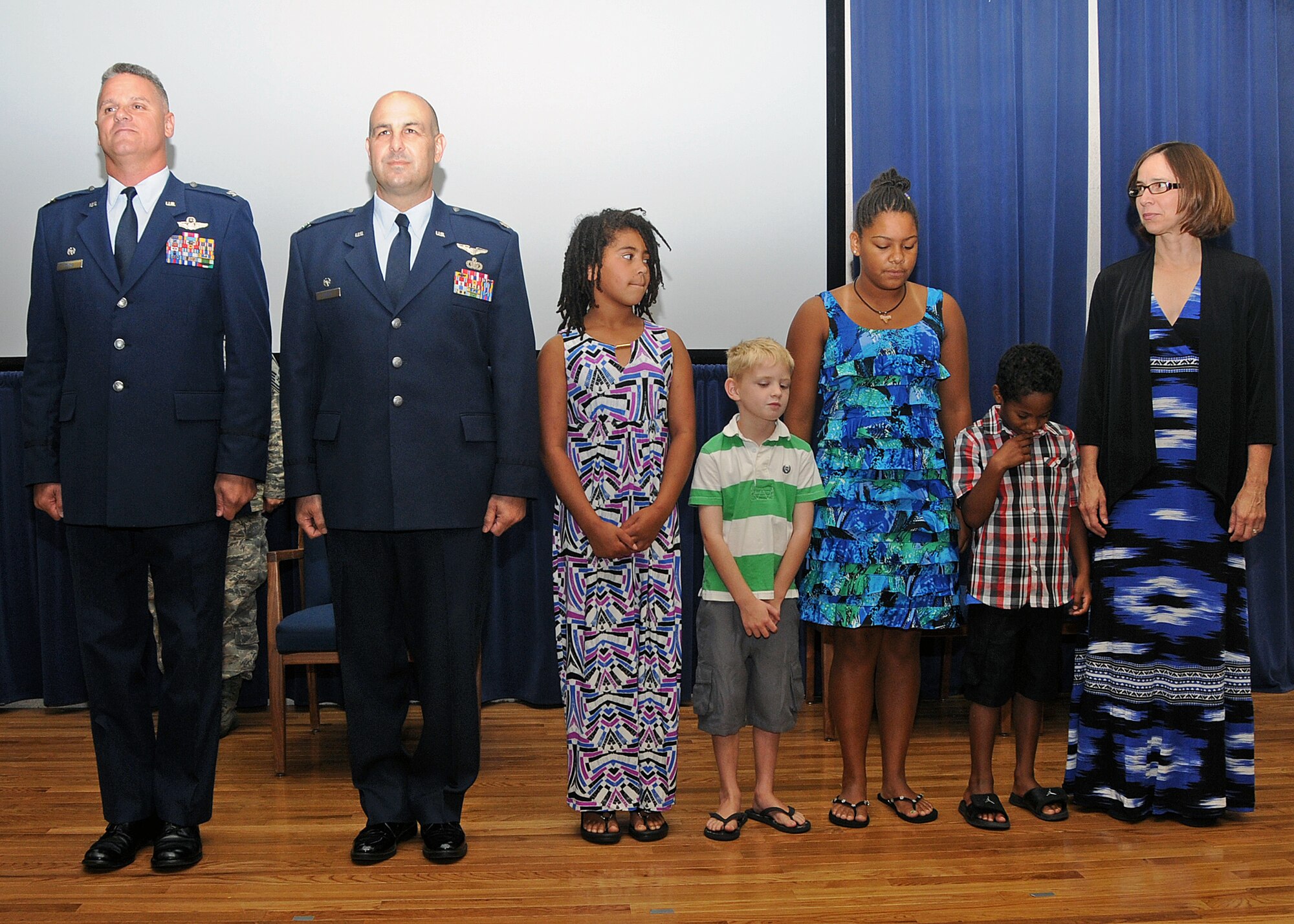 Colonel Arthur Floru, Commander, 143d Airlift Wing, Lieutenant Colonel Anthony Hamel, Commander, 143d Mission Support Group, and LtCol Hamel's family stand for the reading of the promotion order to promote LtCol Hamel to Colonel. National Guard photo by Master Sgt Janeen Miller