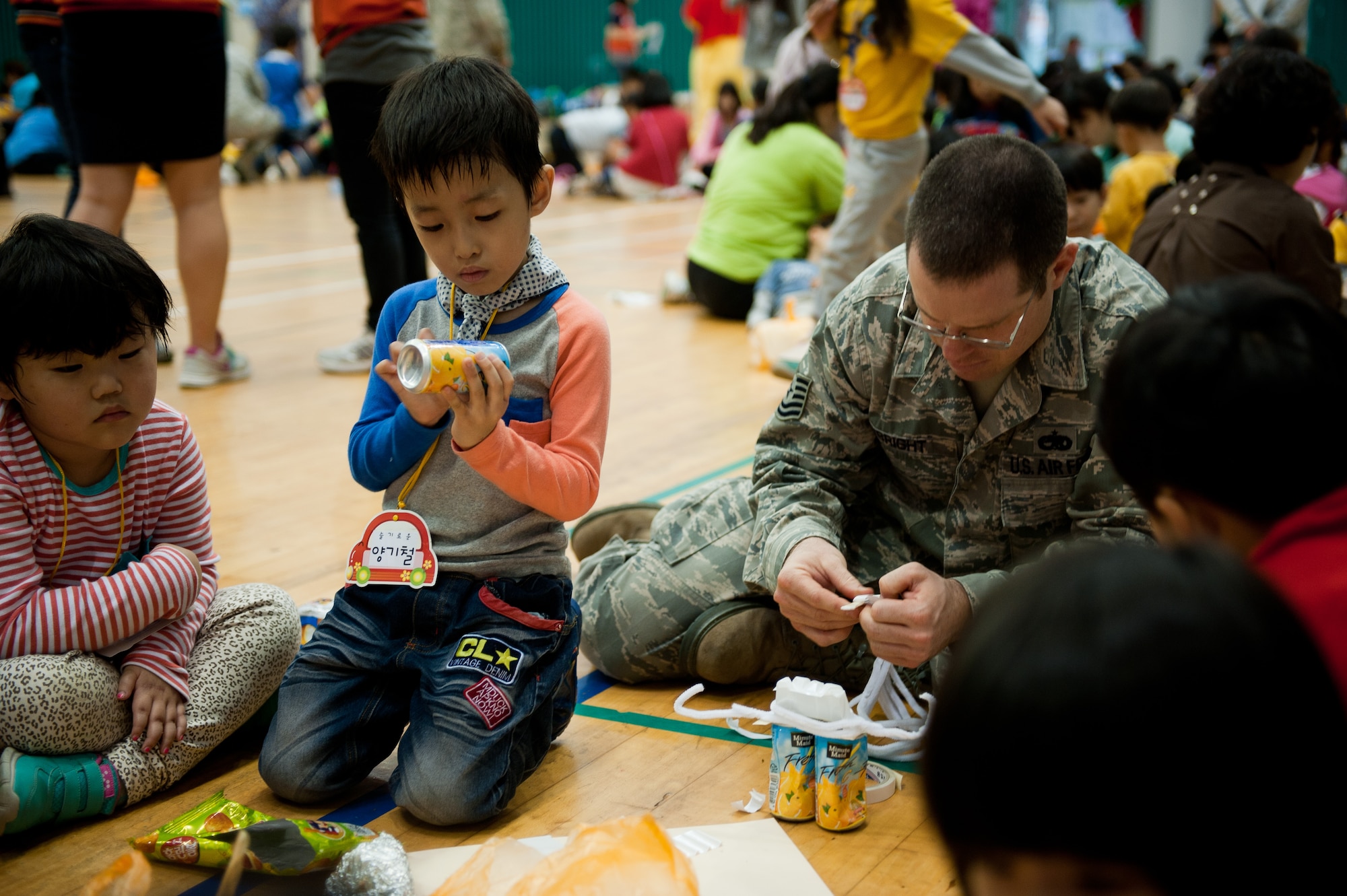 Tech. Sgt. Scott Obright, 8th Maintenance Group, assists children with arts and crafts during the Gunsan City Flower Painting Competition at Gunsan City, Republic of Korea, Oct. 8, 2013. This event was a chance for Airmen to mentor Gunsan children. (U.S. Air Force photo by Senior Airman Clayton Lenhardt/Released)