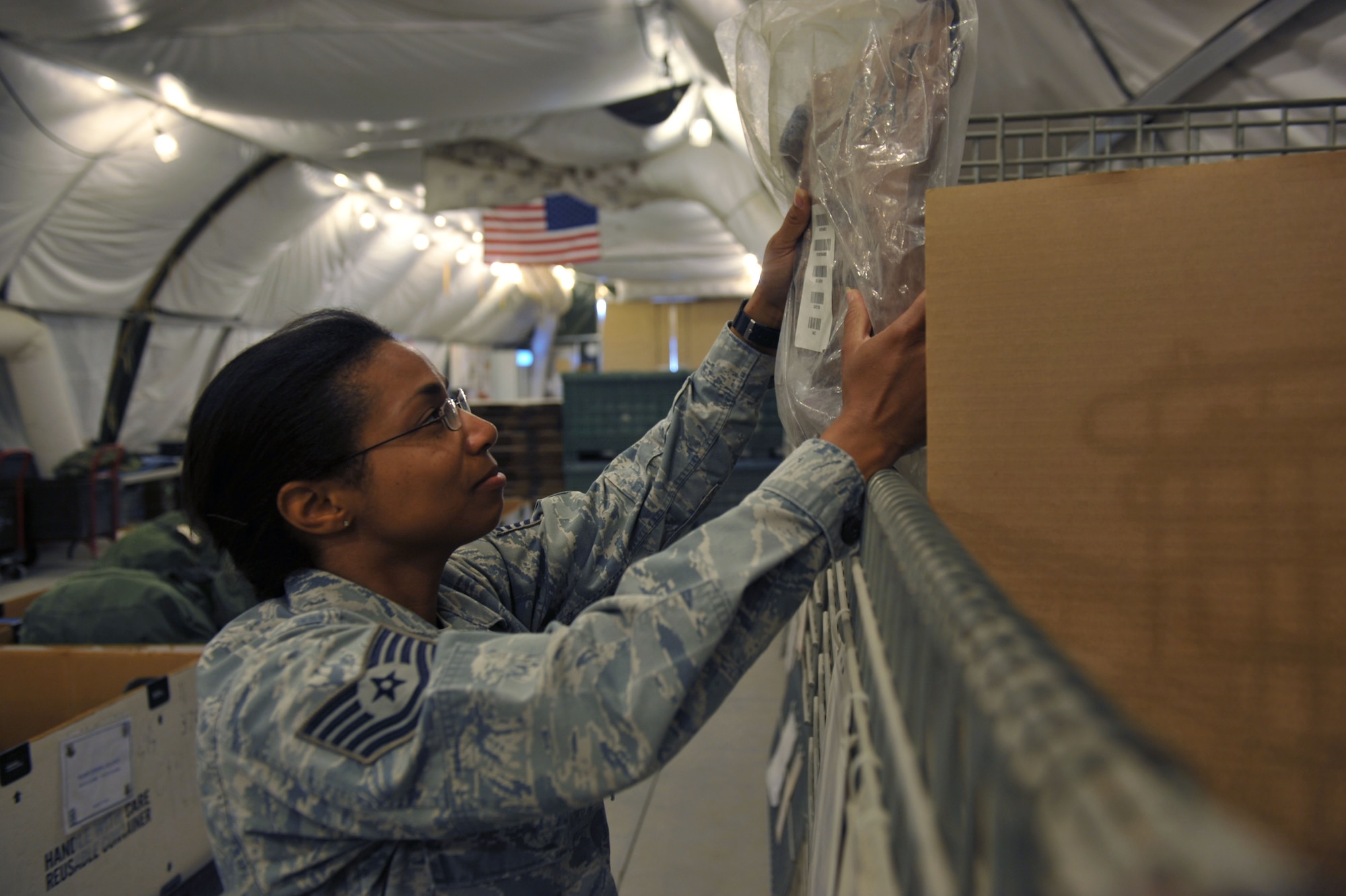 Tech. Sgt. Penelope Patterson checks the expiration date on a joint service lightweight integrated suit technology jacket at the 379th Air Expeditionary Wing in Southwest Asia, Oct. 7, 2013. The Expeditionary Theater Distribution Center return tent receives items issued to members forward deploying and joint expeditionary tasking individuals. Patterson is the 379th Expeditionary Logistics Readiness Squadron return facility NCO in charge deployed from Eglin Air Force Base, Fla., and a Decatur, Ala., native. (U.S. Air Force photo/Master Sgt. David Miller)