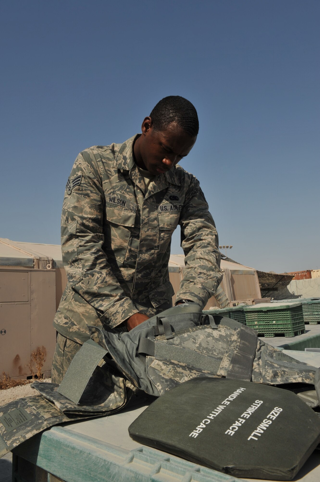 Senior Airman Andrew Wilson places protective plates inside an improved outer tactical vest at the 379th Air Expeditionary Wing in Southwest Asia, Oct. 7, 2013. The Expeditionary Theater Distribution Center issue tent personnel maintain assets for first responders, permanent party and forward deployers to meet mission requirements. Wilson is a 379th Expeditionary Logistics Readiness Squadron issue tent journeyman deployed from Travis Air Force Base, Calif., and a Columbia, S.C., native. (U.S. Air Force photo/Master Sgt. David Miller)