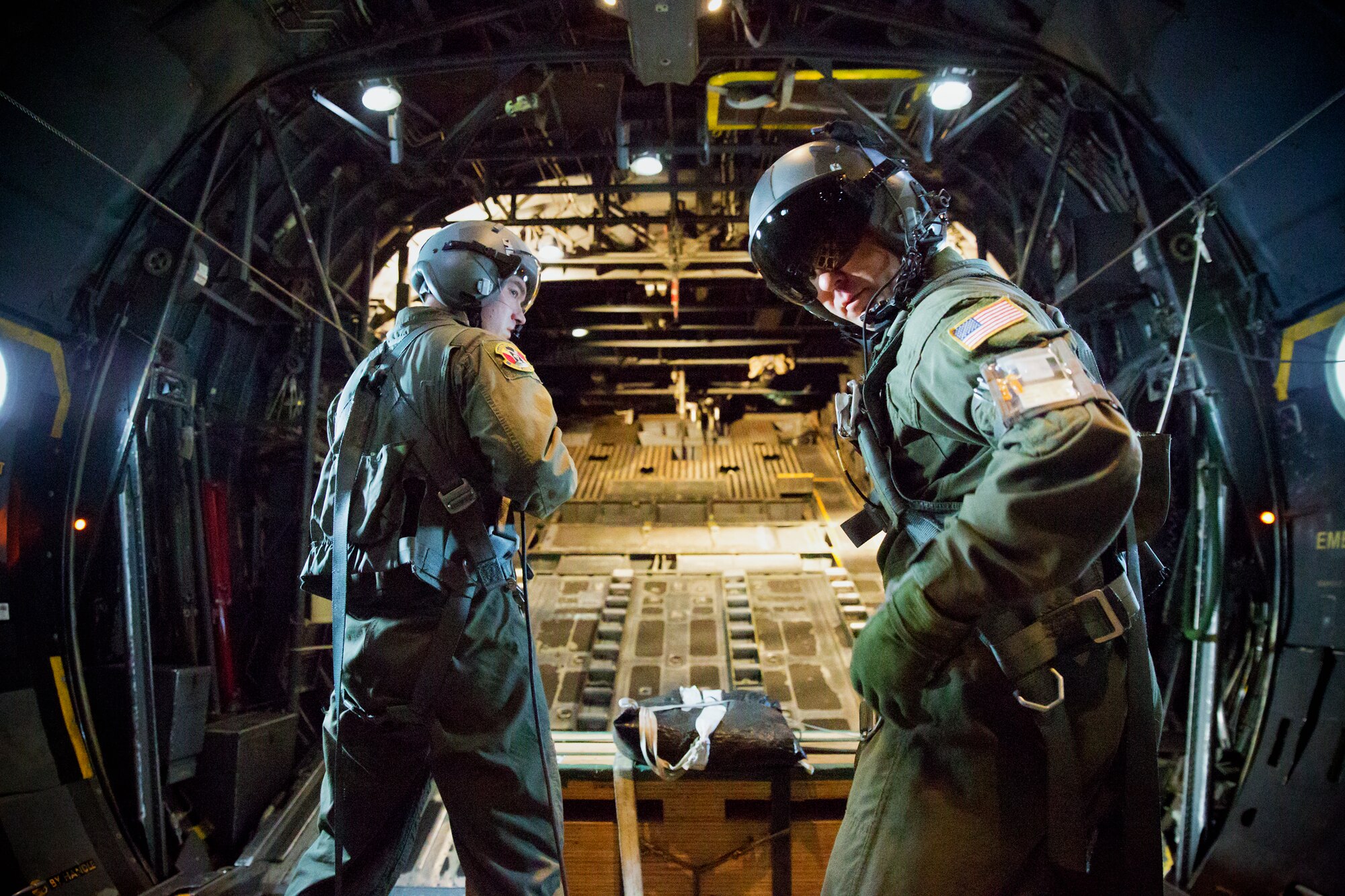 (From left to right) Airman 1st Class Andrew Fox and Tech. Sgt. Todd Bergin, loadmasters assigned to the 36th Airlift Squadron, secure their harnesses before releasing a low-cost, low-altitude cargo bundle during a training mission over Yokota Air Base, Japan, Oct. 8, 2013. LCLA airdrops are a special container delivery system designed to be deployed in austere environments with minimal rigging cost. (U.S. Air Force photo by Osakabe Yasuo/Released)