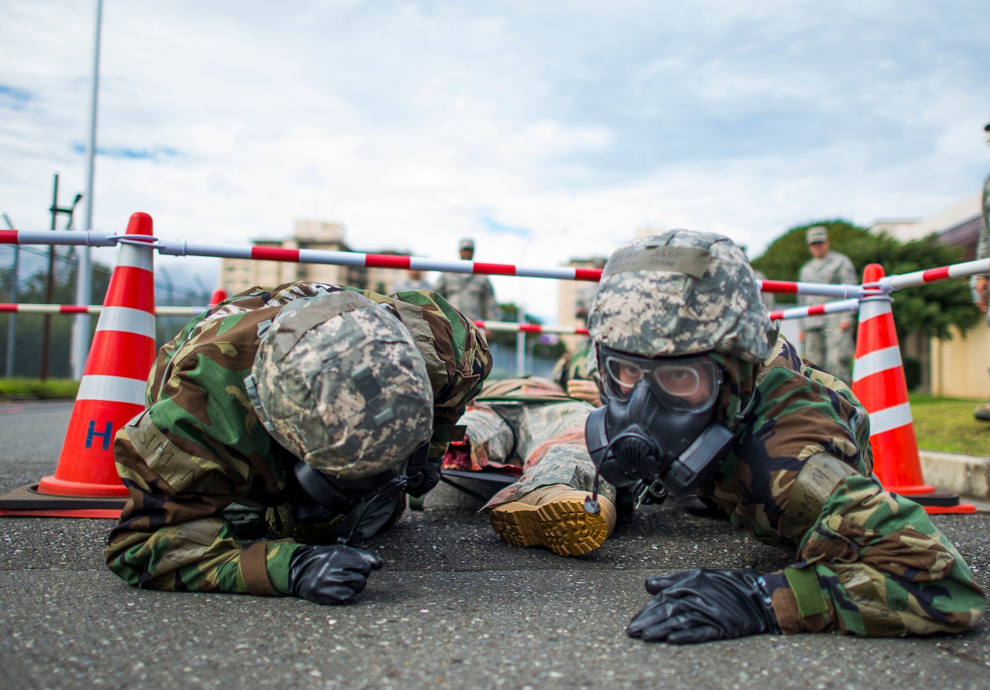 374th Medical Group personnel low-crawl with a simulated victim strapped to a litter during ability to survive and operate (ATSO) training Oct. 9, 2013 at Yokota Air Base, Japan. ATSO training was held to reacquaint Airmen with basic contingency skills. (U.S. Air Force photo by Staff Sgt. Chad C. Strohmeyer/Released)