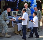 New Hampshire Army National Guard Command Sgt. Maj. John Nanof hands a soccer ball to a student at the Dr. Jose Mendieta School in San Jose Villanueva, La Libertad, El Salvador, on Jan. 27, 2012, as Air Force Maj. Gen. William Reddel and Air Force Maj. Gen Mark Sears look on. The three were members of a group of senior leaders visiting El Salvador as part of the National Guard State Partnership Program with El Salvador. The visit also included the donation of 36 computers to the school and a women's shelter.