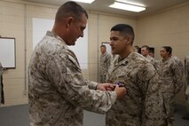 Col Gary F. Keim (left), the commanding officer of Combat Logistics Regiment 27, 2nd Marine Logistics Group, awards the Purple Heart Medal to Sgt. Julian Bejarano Jr., a mortarman with the Battle Skills Training School, CLR-27, during a Purple Heart award ceremony aboard Camp Lejeune, N.C., Oct. 8, 2013. Bejarano received the Purple Heart for wounds sustained from an improvised explosive device blast in Helmand province, Afghanistan, July 5, 2013. 
