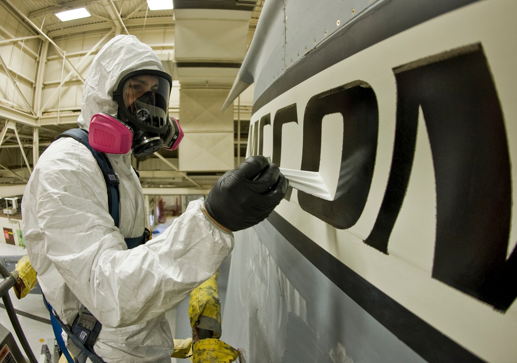 Airman 1st Class Eric Amato, 22nd Maintenance Squadron aircraft structural maintenance journeyman, removes tape from the vertical stabilizer of a KC-135 Stratotanker Oct. 2, 2013, at McConnell Air Force Base, Kan. Airmen wear personal protective equipment to prevent themselves from harmful paint vapors.(US Air Force photo/Airman 1st Class John Linzmeier)