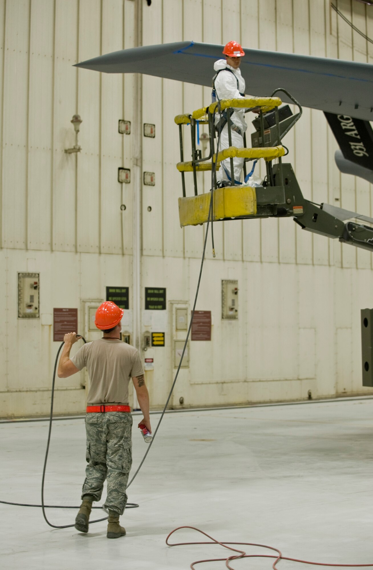 Structural maintenance Airmen, from the 22nd Maintenance Squadron, visually and verbally signal one another while using a JLG Lift. The operator is required to wear a safety harness as a safety measure. (US Air Force photo/Airman 1st Class John Linzmeier)