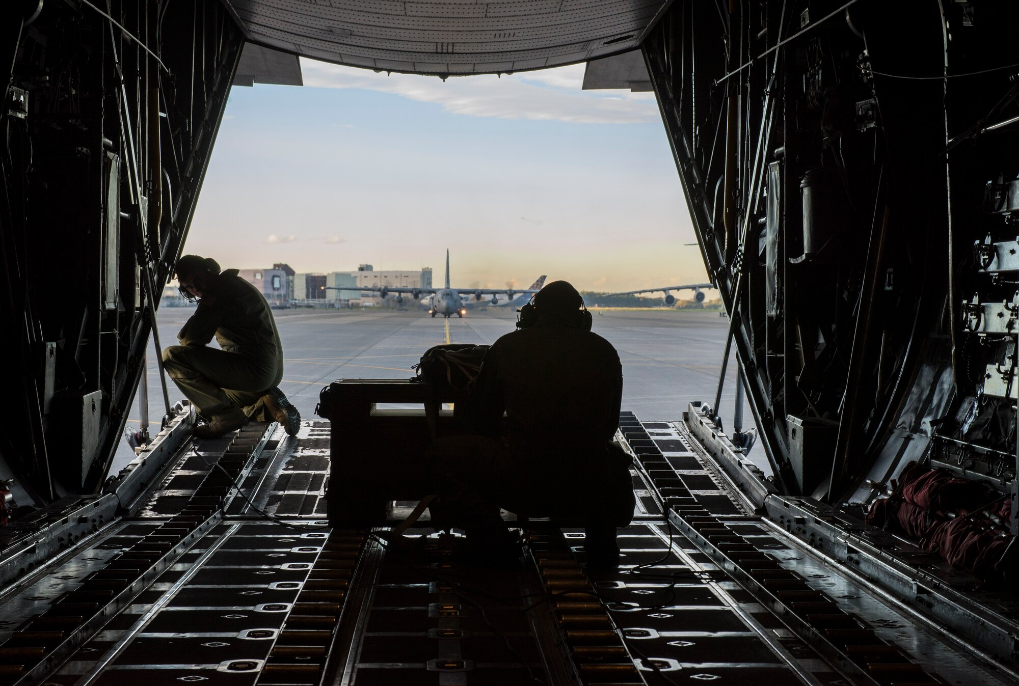 Two loadmasters assigned to the 36th Airlift Squadron look out the back of a C-130 Hercules after a successful mission during Readiness Week at Yokota Air Base, Japan, Oct. 9, 2013. Readiness Week is designed to help Yokota Airmen hone their skills through a series of training scenarios, events and exercises. (U.S. Air Force photo by Senior Airman Michael Washburn/Released)