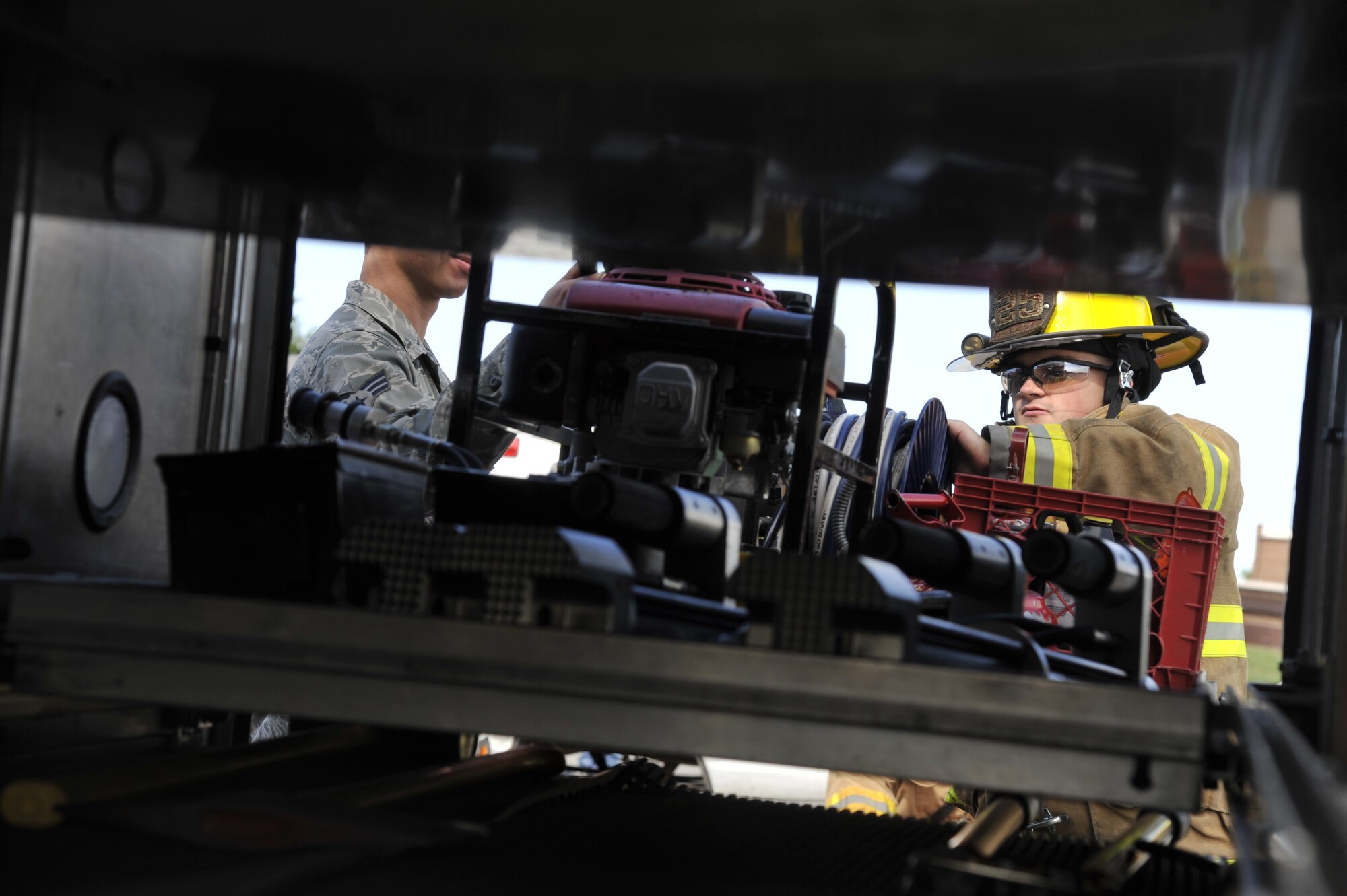 U.S. Air Force Senior Airman Christopher West, 509th Civil Engineer Squadron fire truck driver, right, and Airman 1st Class William Smith, 509th CES firefighter, grab a hydraulic generator during a demonstration at Whiteman Air Force Base, Mo., Oct. 5, 2013. The hydraulic generator is used to power the equipment firefighters operate while performing rescues. This demonstration was done during the kickoff event for the Fire Prevention Week. (U.S. Air Force photo by Airman 1st Class Keenan Berry/Released)