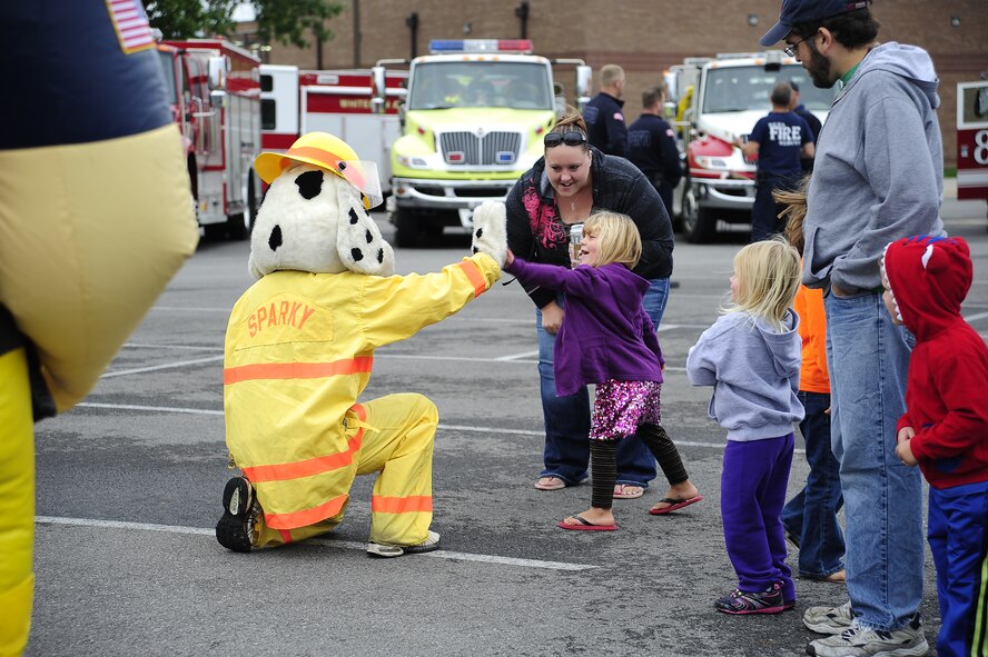 509th Bomb Wing Fire Department mascot Sparky high-fives a fan at the kickoff event for Fire Prevention Week Oct. 5, 2013, at Whiteman Air Force Base, Mo. The 509th Civil Engineer Squadron Fire Department held the event to raise awareness for fire safety in the kitchen. (U.S. Air Force photo by Staff Sgt. Brigitte N. Brantley/Released)