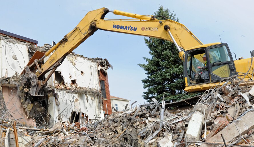 Col. Alex Mezynski, 5th Bomb Wing commander, recently rode the wheel of an excavator for opportunity to take part in the demolishing of Dorm 215 at Minot Air Force Base, N.D. Dorm 215 was originally built in 1958. With the demolishing of this dorm, it leaves only one dormitory left scheduled for demolition. (U.S. Air Force photo/Senior Airman Jose L. Hernandez)