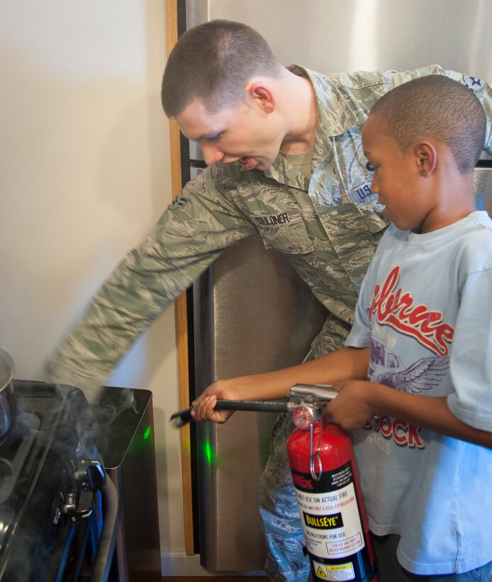 Airman 1st Class Lucas Gouldner, 47th Civil Engineer Squadron crew chief, instructs a child on how to put out a simulated garbage fire Oct. 8, 2013, at Laughlin Air Force Base, Texas. The simulation was part of Fire Prevention and Energy Conservation week at Laughlin where 47th CES members went to several base organizations and instructed on how to handle certain fire emergencies. (U.S. Air Force photo/Senior Airman John D. Partlow)