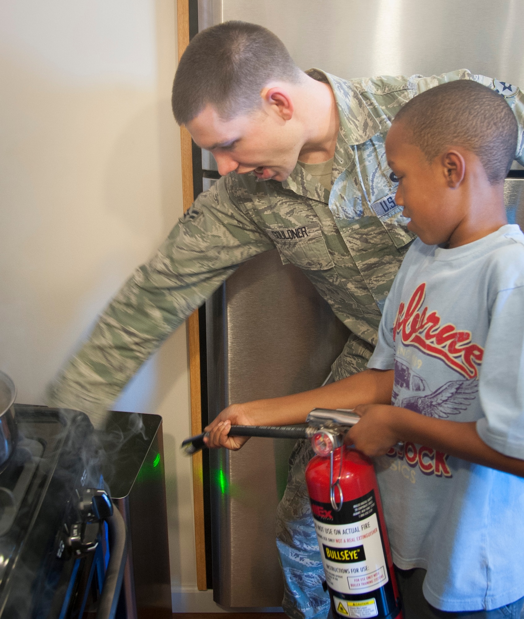 Airman 1st Class Lucas Gouldner, 47th Civil Engineer Squadron crew chief, instructs a child on how to put out a simulated garbage fire Oct. 8, 2013, at Laughlin Air Force Base, Texas. The simulation was part of Fire Prevention and Energy Conservation week at Laughlin where 47th CES members went to several base organizations and instructed on how to handle certain fire emergencies. (U.S. Air Force photo/Senior Airman John D. Partlow)