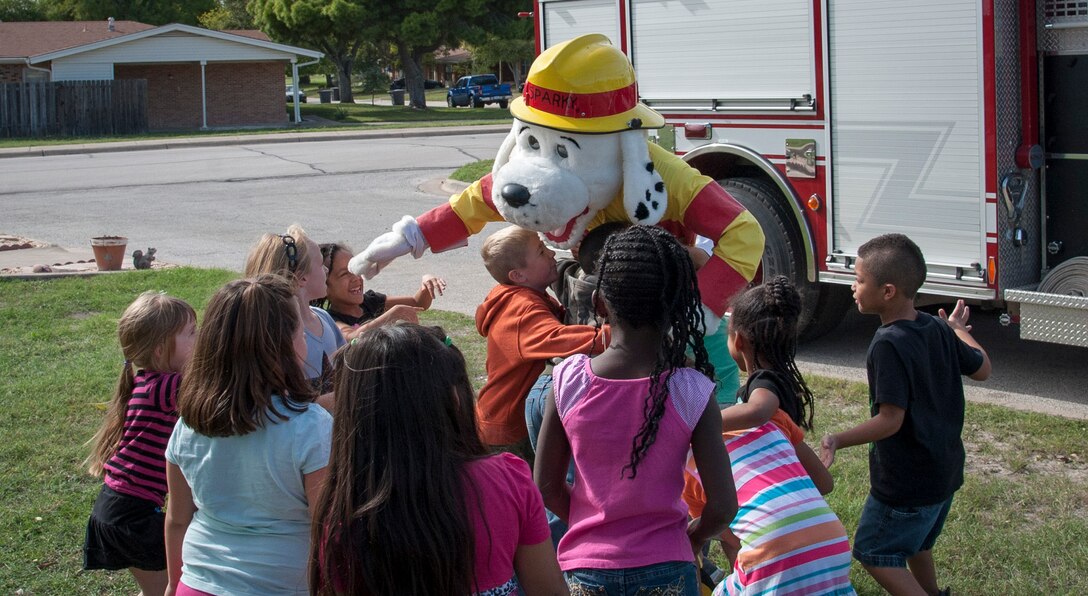 Sparky the fire dog greets children beside a fire truck Oct. 8, 2013, at Laughlin Air Force Base, Texas. Sparky met with the kids as part of Fire Prevention and Energy Conservation Week here to educate base members about ways to save and stay safe. (U.S. Air Force photo/Senior Airman John D. Partlow)