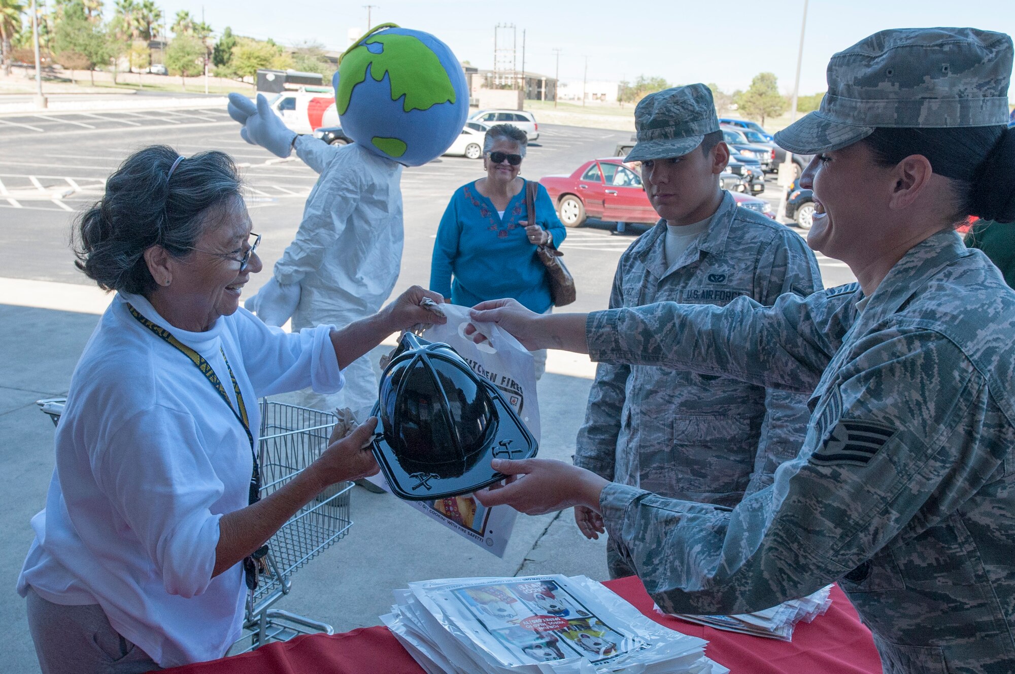 A patron at the base Exchange puts out a simulated fire Oct. 8, 2013, at Laughlin Air Force Staff Sgt. Krystell Clemons, 47th Civil Engineer Squadron crew chief, hands fire prevention literature to a base Exchange customer Oct. 8, 2013, at Laughlin Air Force Base, Texas. Oct. 7 - 11 is Fire Prevention and Energy Conservation Week, and the 47th CES personnel are going around base to educate base members on how to stay safe and save money. (U.S. Air Force photo/ Senior Airman John D. Partlow)