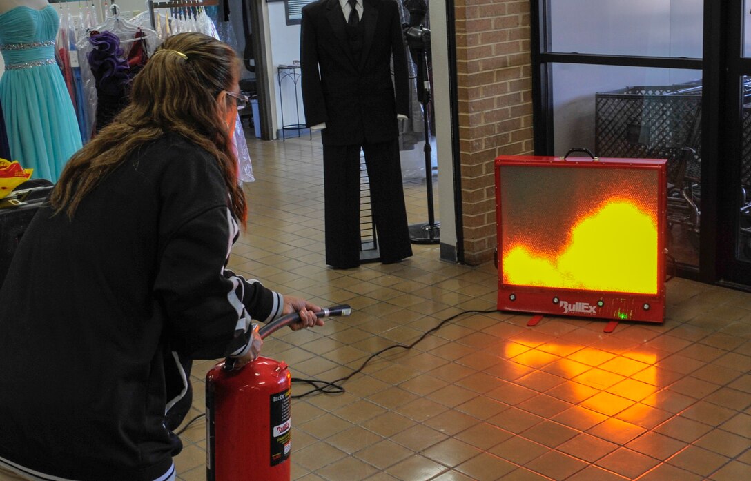 A patron at the base Exchange puts out a simulated fire Oct. 8, 2013, at Laughlin Air Force Base, Texas. The display was part of Fire Prevention and Energy Conservation week, where the 47th Civil Engineer Squadron personnel went around base to demonstrate how to put out common fires. (U.S. Air Force photo/ Senior Airman John D. Partlow)