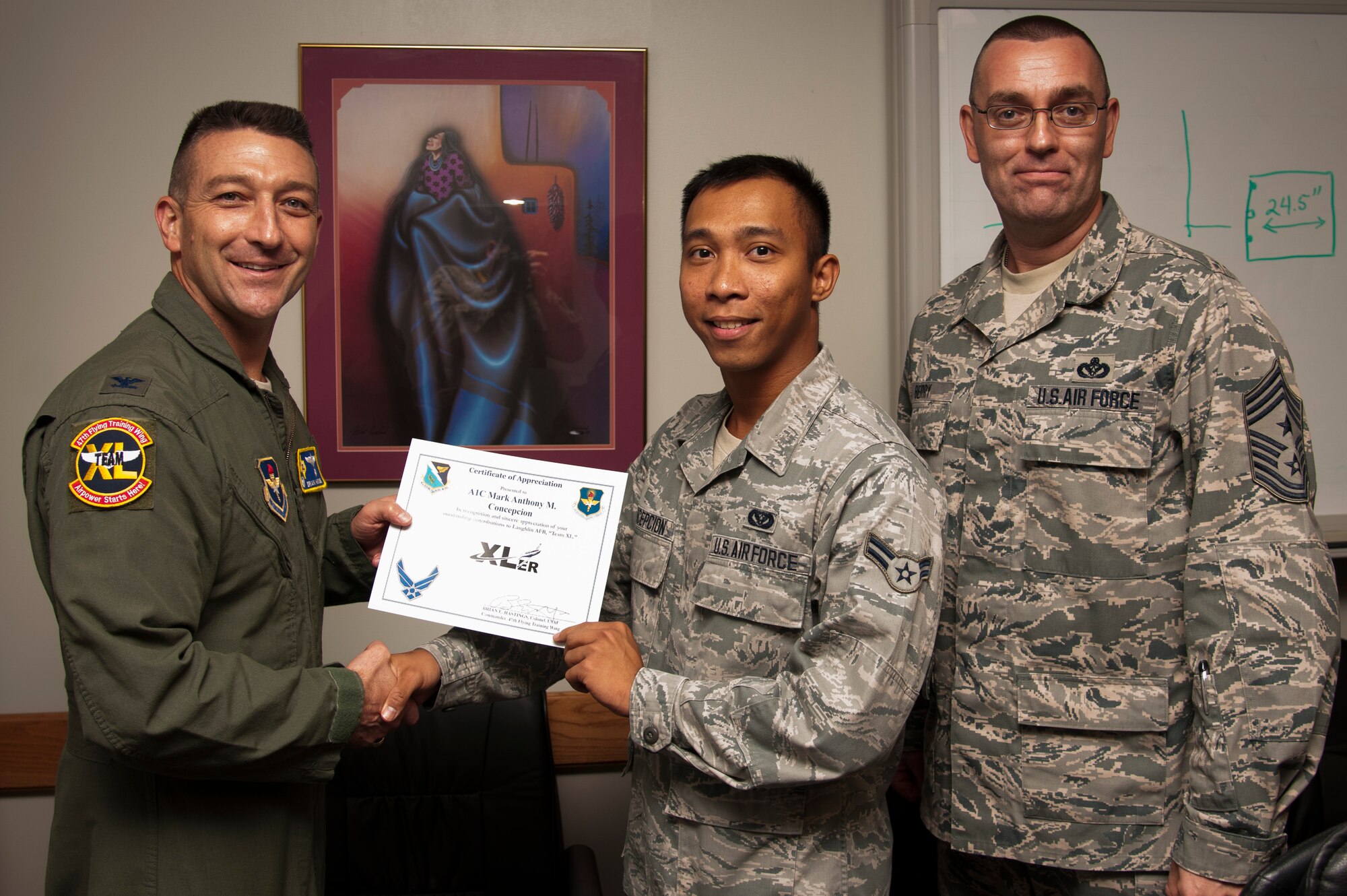 Airman 1st Class Mark Anthony Concepcion, 47th Civil Engineer Squadron engineering apprentice, poses with Col. Brian Hastings, 47th Flying Training Wing commander, and Chief Master Sgt. Garry Berry, 47th FTW command chief, after being presented the XLer of the week award here Oct. 2, 2013. The XLer is a weekly award chosen by wing leadership and given to those who consistently make outstanding contributions to Laughlin and their unit. (U.S. Air Force photo/Senior Airman John D. Partlow)