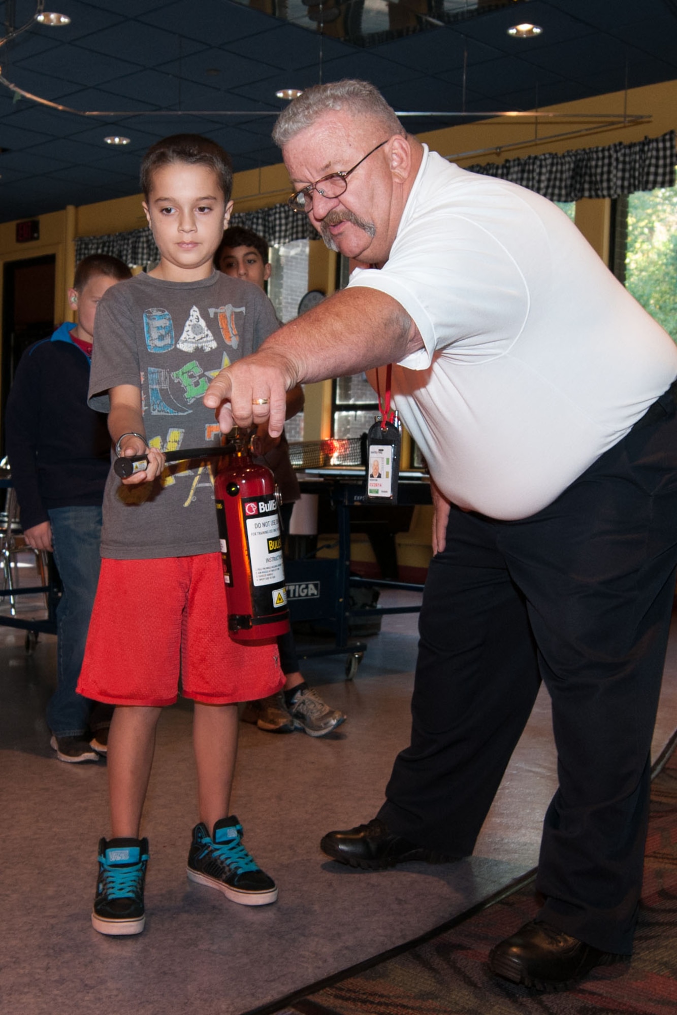 HANSCOM AIR FORCE BASE, Mass. -- Robert Kenyon, Hanscom Fire Prevention captain, instructs Jason Clemsic and other children on the proper use of a fire extinguisher during a Fire Prevention Week activity at the Youth Center Oct. 8. Throughout the week the Fire Department also visited the Child Development Center, Middle School and Primary School to teach children how to use a fire extinguisher. (U.S. Air Force photo by Mark Herlihy)