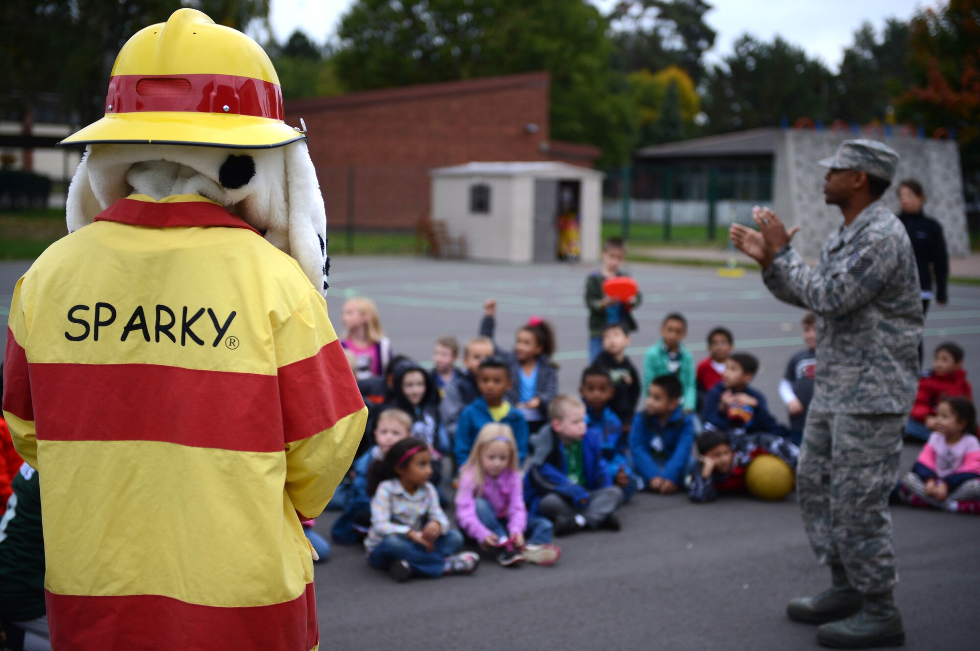 SPANGDAHLEM AIR BASE, Germany – Sparky the Fire Dog looks on as Tech. Sgt. Mario Rainge, 52nd Civil Engineer Squadron NCO in charge of fire prevention from Phoenix, talks to children about fire prevention Oct. 9, 2013. Fire prevention week increases safety and awareness helping to prevent the cause of a fire. (U.S. Air Force photo by Airman 1st Class Kyle Gese/Released)