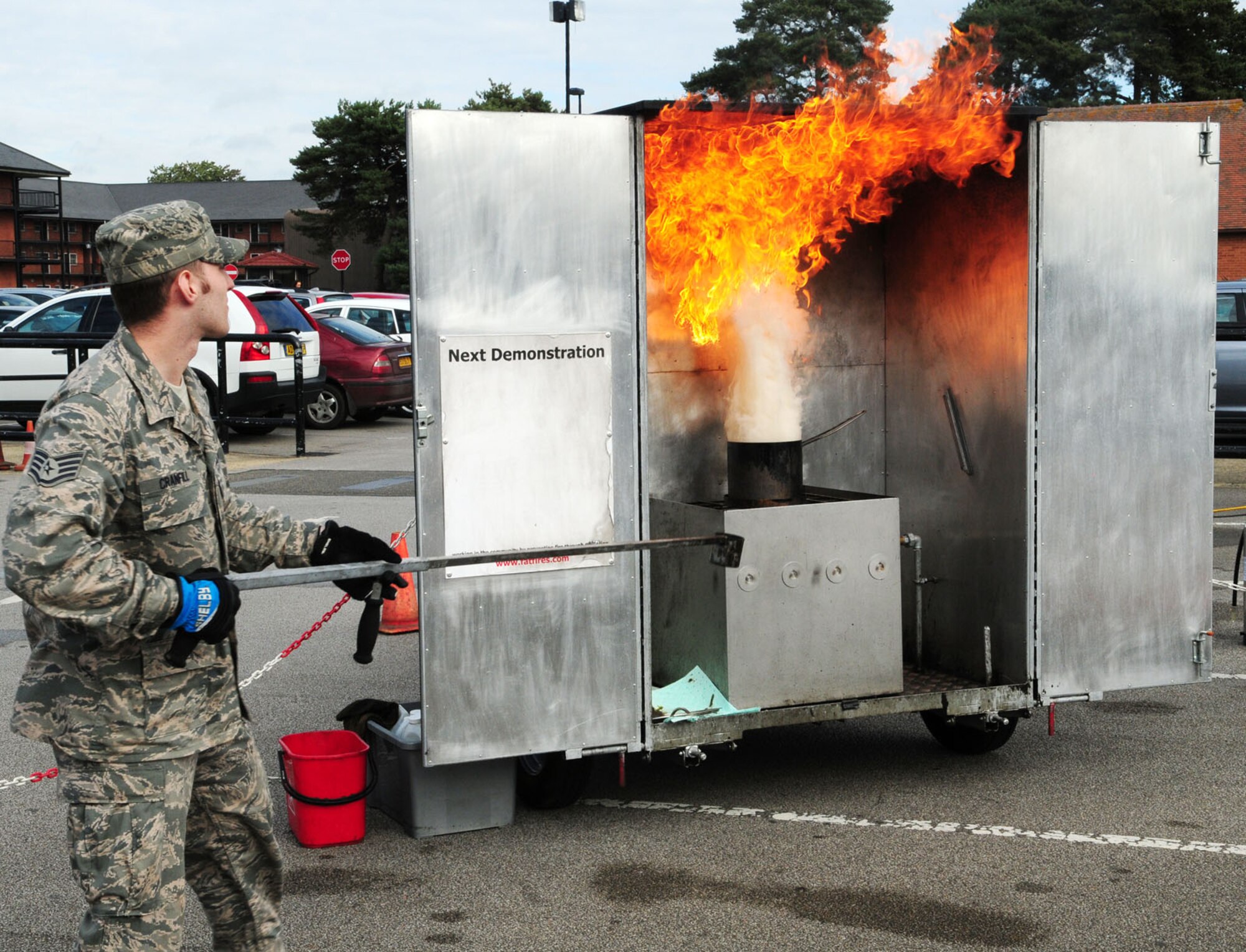 A grease pan fire throws flames into the air as U.S. Air Force Staff Sgt. Andrew Cranfill, 100th Civil Engineer Squadron Fire Department firefighter from Woburn, Mass., demonstrates the dangers of putting water onto the boiling oil. Fire Prevention Week is Oct. 6 to 12 and the fire prevention office organized events throughout the week to highlight the theme of "Prevent Kitchen Fires." (U.S. Air Force photo by Karen Abeyasekere/Released)
