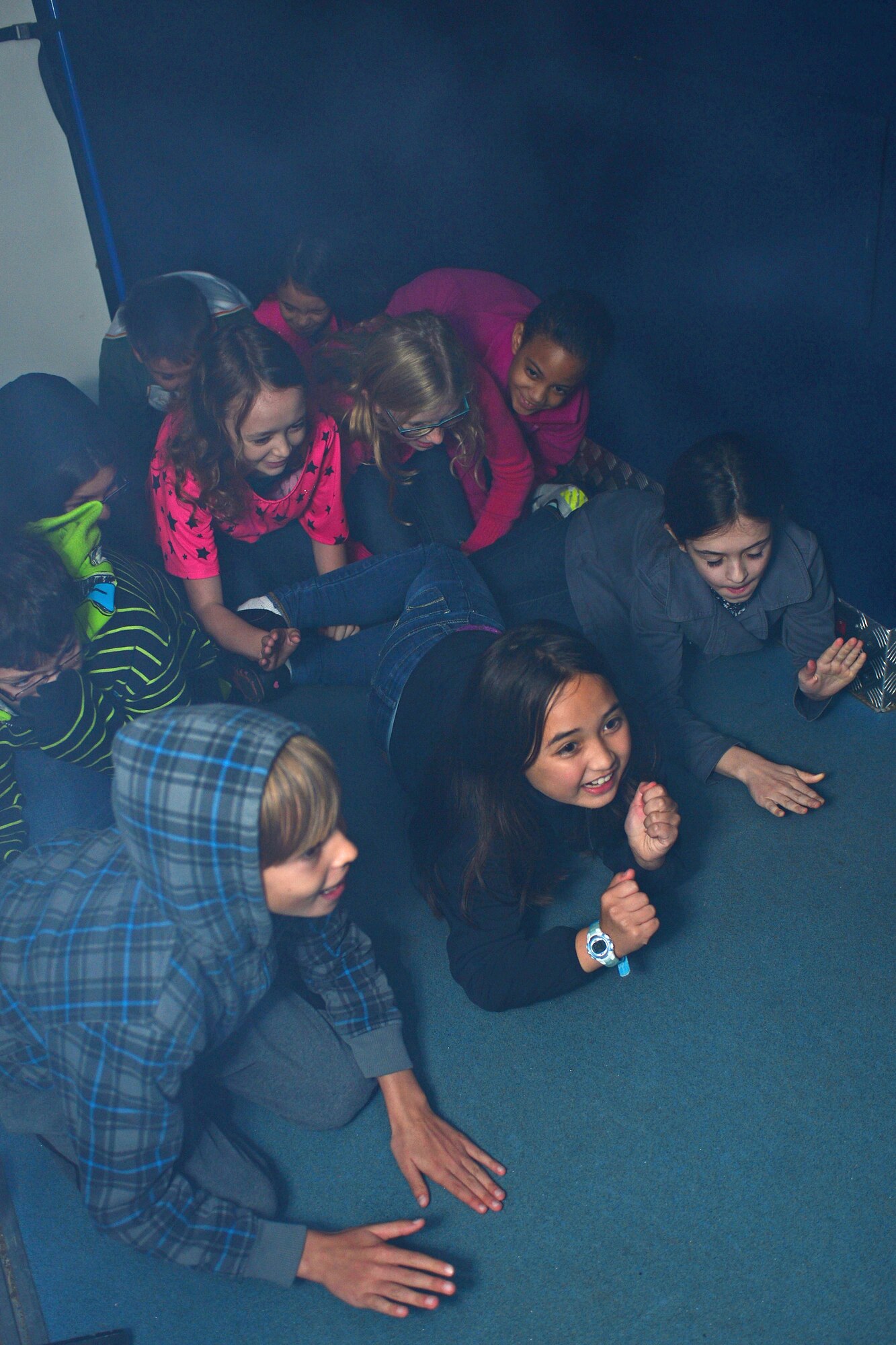 Fourth grade students from the intermediate school at Royal Air Force Lakenheath, England, practice how to crawl out of a mock bedroom room fire while in a mobile fire simulation trailer Oct. 8, 2013. Firefighters from the Suffolk Fire and Rescue Service worked with 48th Civil Engineering Squadron firefighters to help raise awareness about fire safety as a part of National Fire Prevention Week. (U.S. Air Force photo by Airman 1st Class Dana J. Butler/Released)