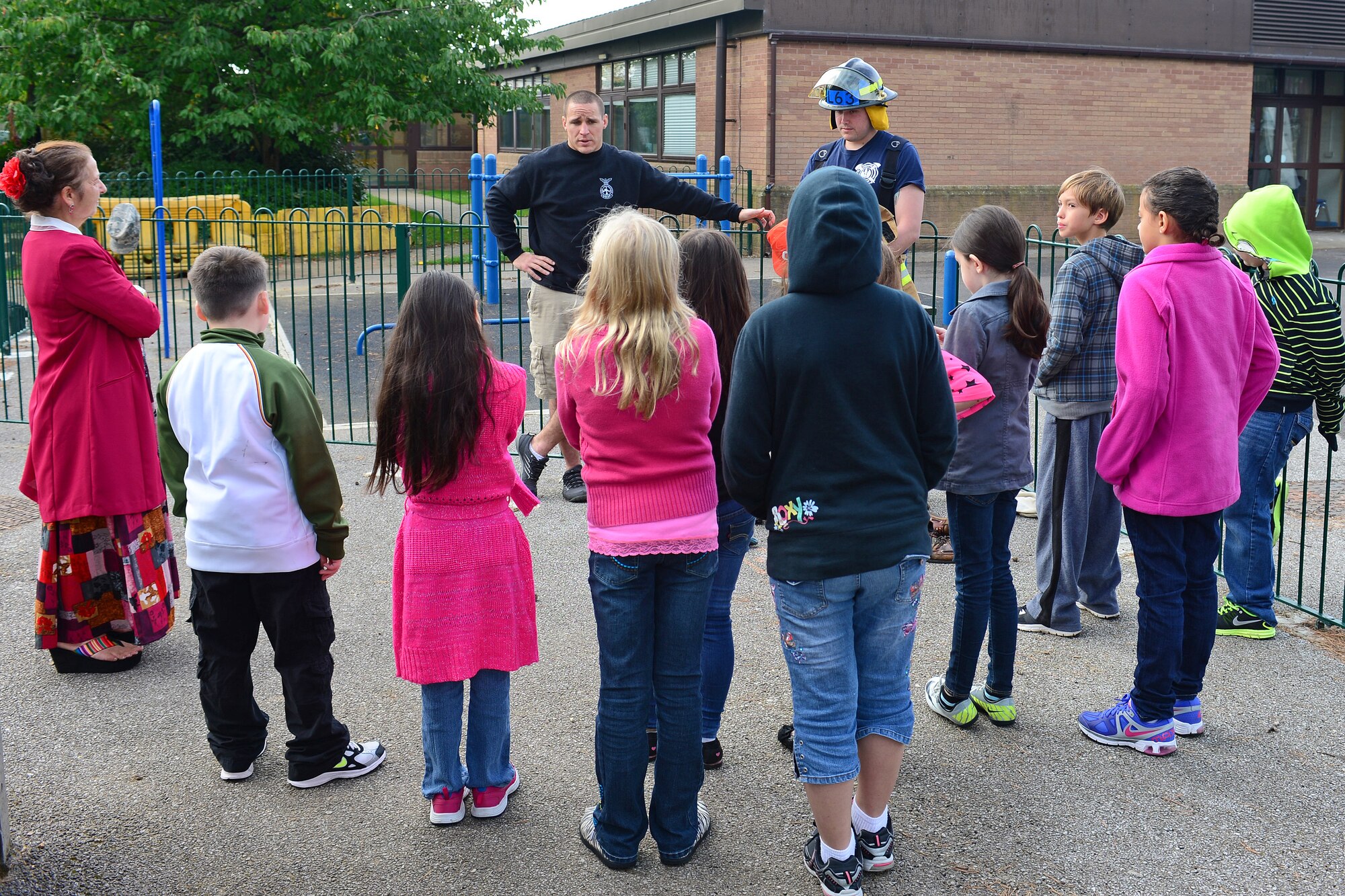 Fourth grade students from the intermediate school at Royal Air Force Lakenheath, England, listen to Staff Sgt. Matthew Duggan, 48th Civil Engineering Squadron Fire Department crew chief, and Airman 1st Class Liam Lashley, 48th CES Fire Department firefighter, as they explain the importance of fire safety Oct. 8, 2013. Firefighters from the Suffolk Fire and Rescue Service worked with 48th CES firefighters to help raise awareness about fire safety as a part of National Fire Prevention Week. (U.S. Air Force photo by Airman 1st Class Dana J. Butler/Released)