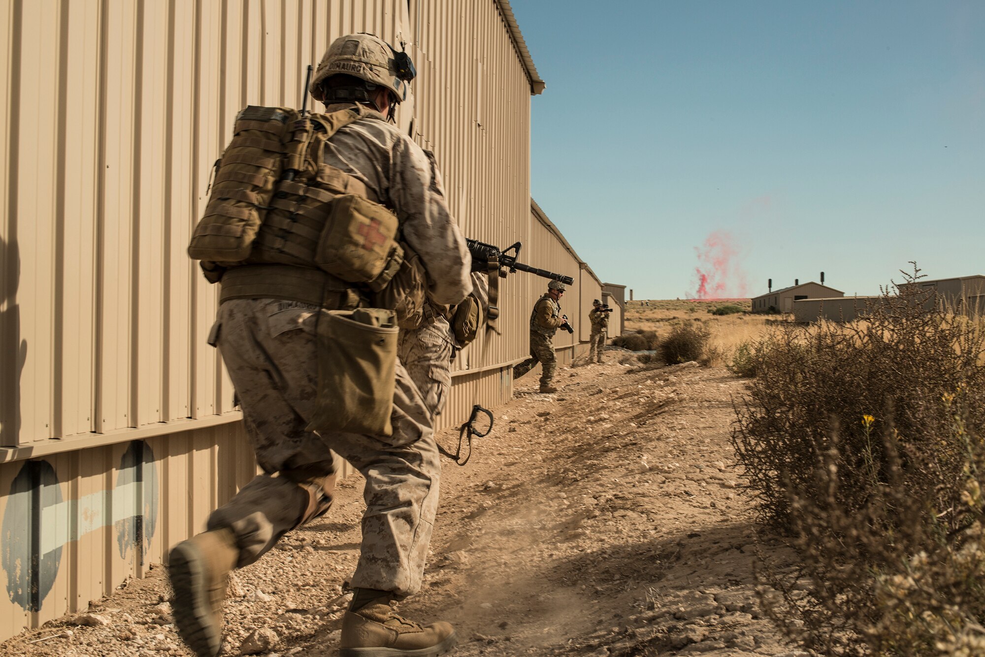U.S. Marine Capt. Erich Lloyd, 1st Air Naval Gunfire Liaison Company forward air controller deployed from Camp Pendleton, Calif., moves forward, bounding toward enemy contact, as two U.S. Air Force combat photojournalists from the 366th Fighter Wing Public Affairs office document the movement, during exercise Mountain Roundup 2013 at Juniper Butte Range, about 70 miles from Mountain Home Air Force Base, Idaho, Oct. 8, 2013. “Our mission during the urban assault was to attach to a U.S. Army unit and assault through the objective looking for chemical weapons - Serine gas - near the rail yard,” said Lloyd, who led a four-man fire-power control team, while commanding a second FIC and controlling CAS for the mission.  (U.S. Air Force photo by Master Sgt. Kevin Wallace/RELEASED)