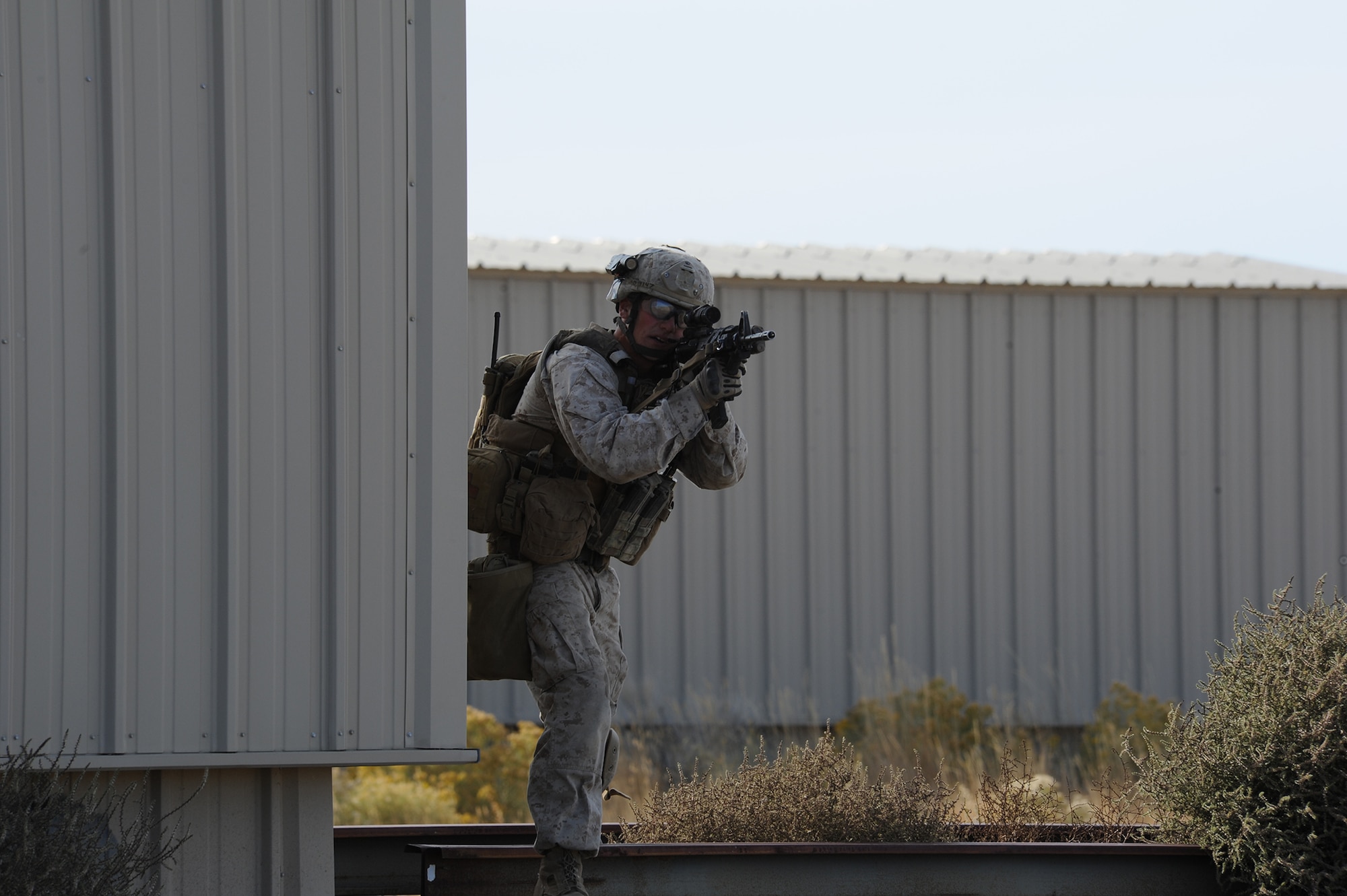 U.S. Marine Cpl. Andrew Dimauro, 1st Air Naval Gunfire Liaison Company forward air controller deployed from Camp Pendleton, Calif., scans a sector of fire and anticipates enemy contact during an exercise urban combat scenario during exercise Mountain Roundup 2013 at Juniper Butte Range, about 70 miles from Mountain Home Air Force Base, Idaho, Oct. 8, 2013. In Dimauro’s exercise scenario, he attached to a U.S. Army unit and assault through the objective looking for chemical weapons - Serine gas - near the rail yard. Dimauro also assisted the U.S. Air Force’s 366th Fighter Wing Public Affairs office by wearing one of their helmet cameras, to capture video footage during the exercise. (U.S. Air Force photo by Master Sgt. Kevin Wallace/RELEASED)