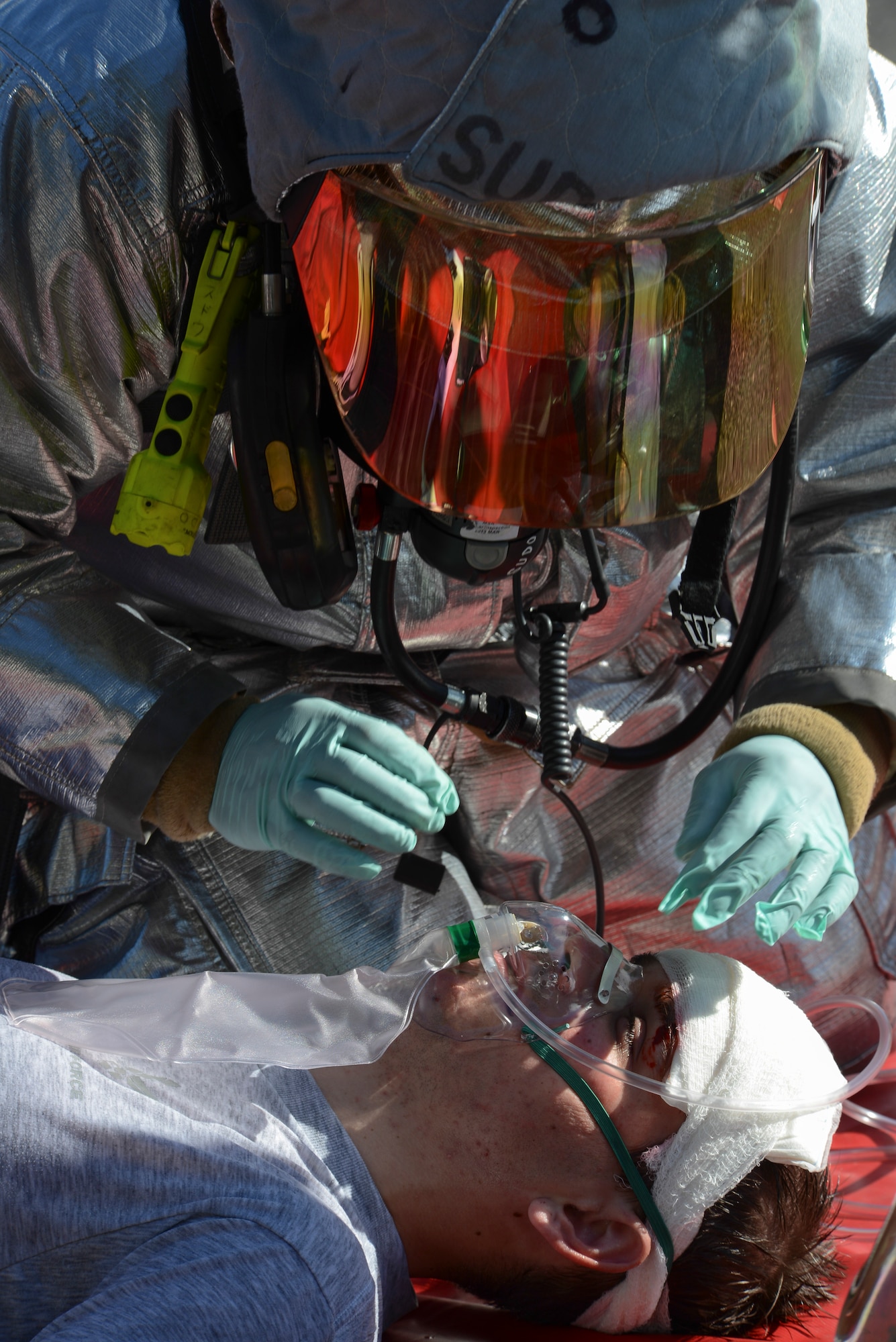 A 374th Civil Engineer Squadron fire fighter places an oxygen mask on Airman 1st Class David Danford, 374th Airlift Wing, after addressing his moulaged head wound during an emergency management exercise as part of Readiness Week at Yokota Air Base, Japan, Oct. 10, 2013. The training allowed first responders a chance to practice their emergency response skills. (U.S. Air Force photo by Senior Airman Michael Washburn/Released)  