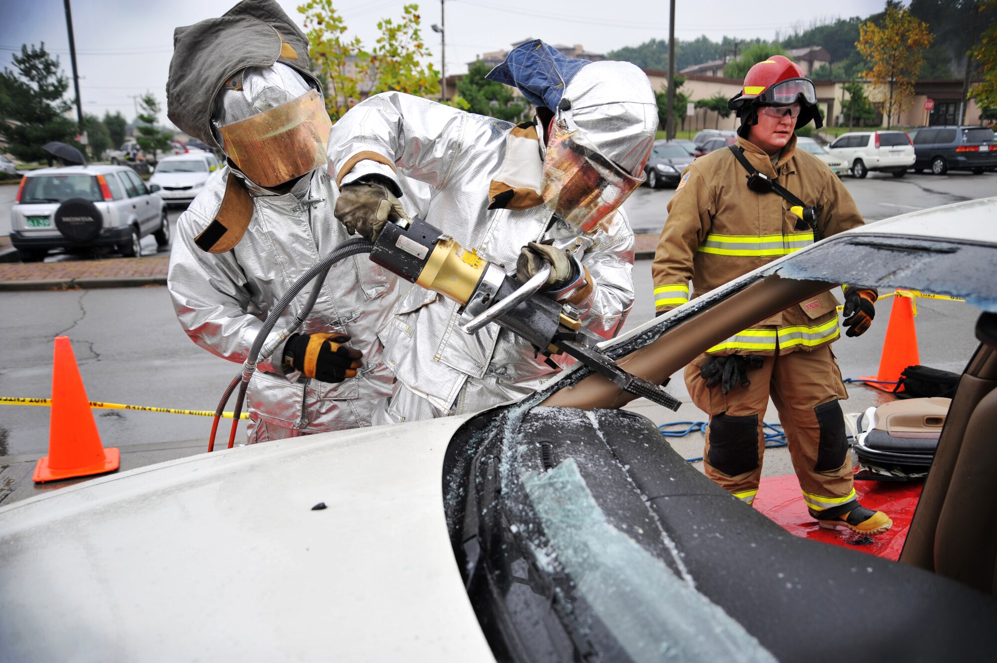 Senior Airmen Robert McCallon, center, and Senior Airman David Easterlund, 51st Civil Engineer Squadron fire and emergency services flight firefighters, prepare to remove the roof of a vehicle during a vehicle extrication demonstration at Osan Air Base, Republic of Korea, Oct. 8, 2013. The demonstration was held to kick off fire prevention week. (U.S. Air Force photo/Staff Sgt. Emerson Nuñez)