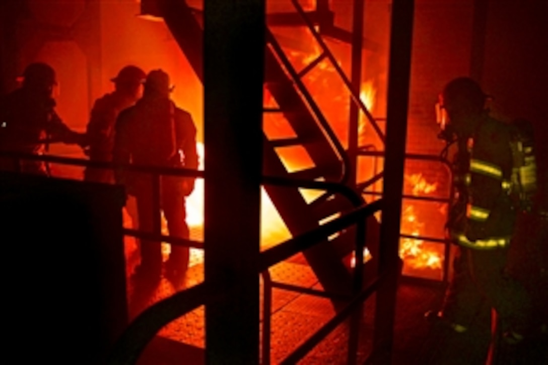 U.S. sailors assigned to the guided-missile destroyer USS Stethem 63 and the amphibious dock landing ship USS Ashland 48 work together to put out a fire during a shipboard firefighting course at Surface Warfare Officer School Engineering Learning Site in Yokosuka, Japan, Oct. 8, 2013. The school provides education and training to support surface Navy requirements that prepare officer and enlisted engineers to serve at sea.