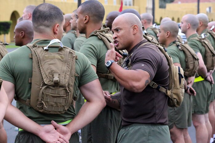 A student (green shirt) is corrected by an instructor during a formation before running his initial Physical Fitness Test aboard the depot, Oct. 1. Students are held to a higher standards and are expected perform to give maximum effort throughout the duration of the course.