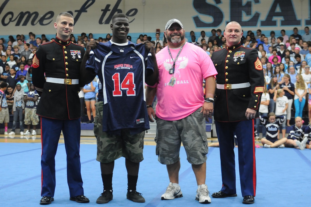Marines of Recruiting Station Jacksonville present a Semper Fidelis All-American Bowl jersey to high school senior Poona Ford during a pep rally at Hilton Head High School in Hilton Head, S.C., Oct. 11, 2013. Kelleher was selected to participate in the Semper Fidelis All-American Bowl in January in Carson, Calif. Kelleher plays defensive tackle on the Hilton Head High School varsity football team.