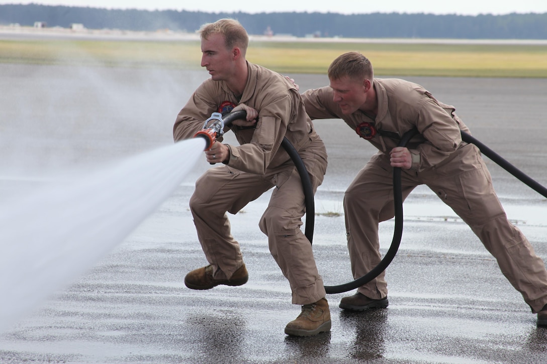 Lance Cpl. John M. Glasbrooks and Pfc. Luke Huls, Aircraft Rescue and Fire Fighting specialists with Cherry Point’s Crash Fire Rescue, execute maneuver procedures as they make their way to a controlled aircraft fire Oct. 3. The Marines participated in shipboard aircraft firefighting training that prepared them to handle worst-case scenarios that may arise while deployed at sea.   