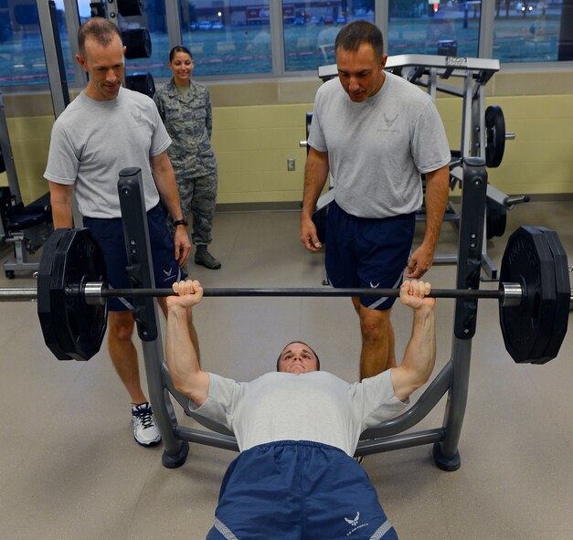 Col. Leland Bohannon, left, 2nd Bomb Wing vice commander, and Chief Master Sgt. Curtis Storms, 2nd BW command chief, spot Airman 1st Class Michael Condon, 2nd Comptroller Squadron finance management journeyman, as he bench presses at the Senior Airman Bryan R. Bell Fitness Center on Barksdale Air Force Base, La., Oct. 11, 2013. Condon was the first person to use the recently re-opened weight room. The old weight room is currently being renovated into the new aerobics room. (U.S. Air Force photo/Senior Airman Micaiah Anthony)
