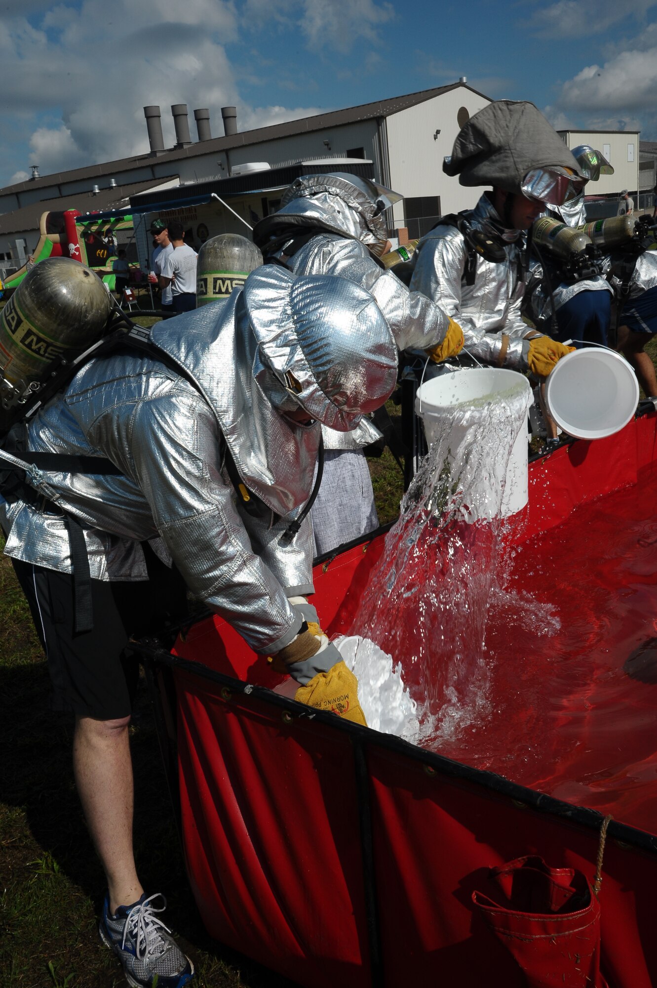 A team of Airmen fill small buckets of water to fill a larger bucket of water during the Water Bucket Brigade at the Base Fire Muster Oct. 10 at the Old Fuels Yard on Simler Blvd. The activity required not only strength and endurance, but teamwork. (U.S. Air Force Photo/Airman Daniel Lile)