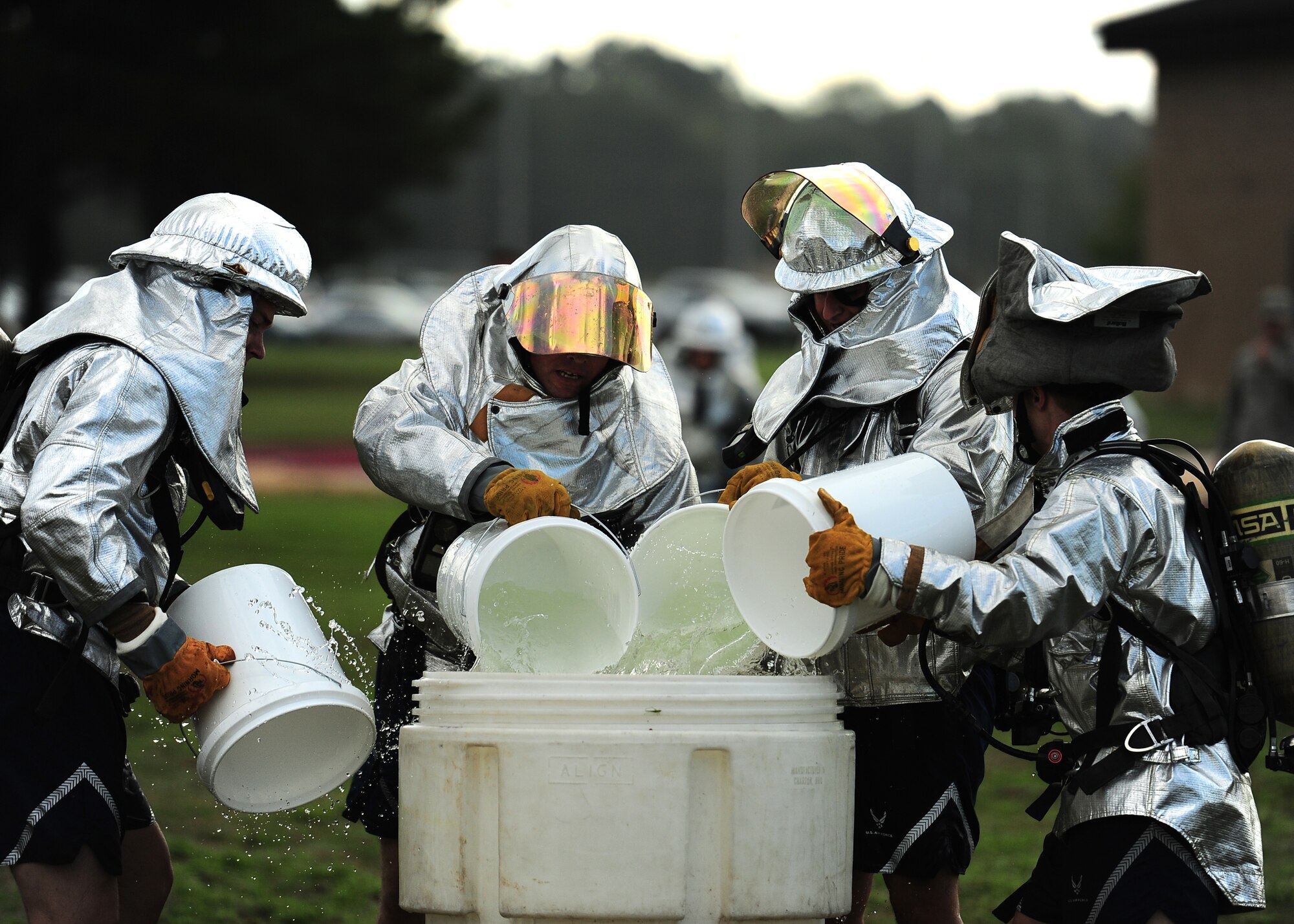 A team of Airmen dump water into a large bucket using smaller buckets during the Water Bucket Brigade at the Base Fire Muster Oct. 10 at the Old Fuels Yard on Simler Blvd. The activity required not only strength and endurance, but teamwork. (U.S. Air Force Photo/Airman 1st Class Stephanie Englar)
