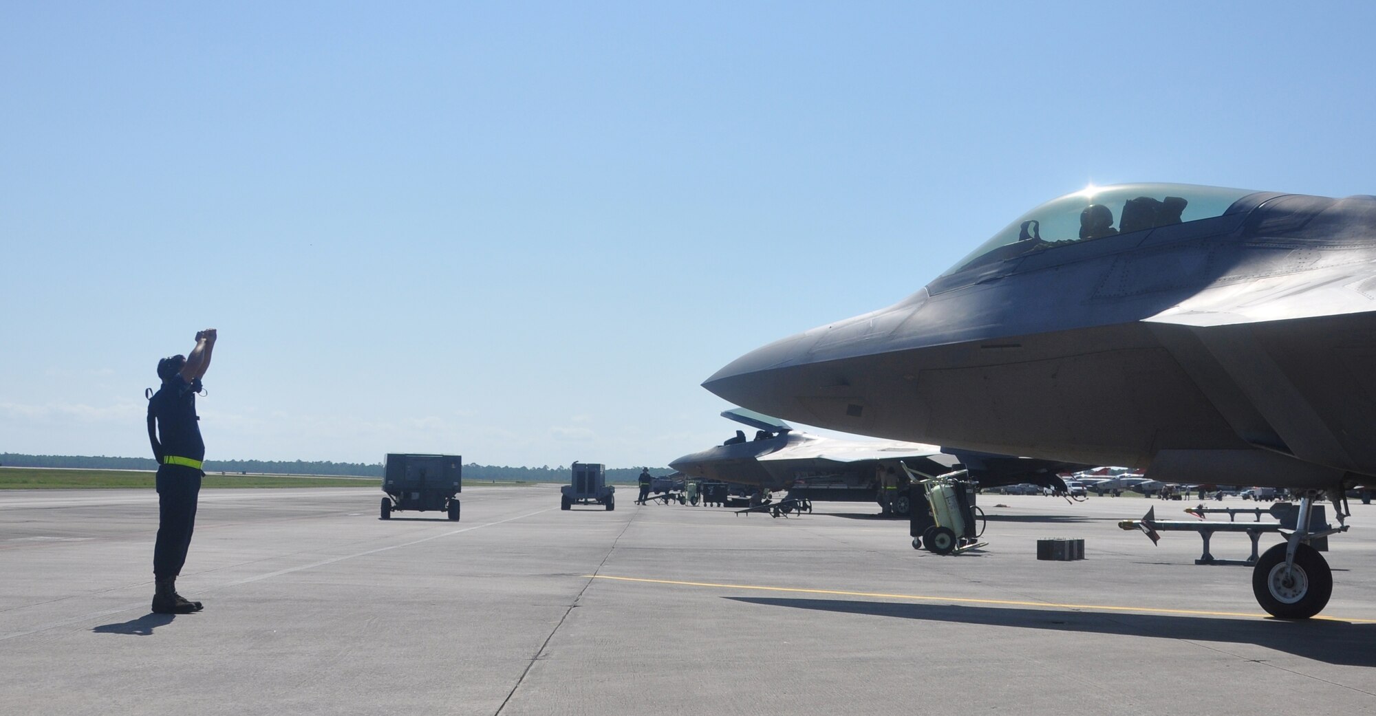 A crew chief guides an F-22 Raptor pilot while he parks during an in-place deployment on Tyndall's flightline Sept. 19. They were participating in WSEP, the Air Combat Command's air-to-air Weapon System Evaluation Program also known as Combat Archer. (U.S. Air Force photo by Airman 1st Class Alex Echols)
