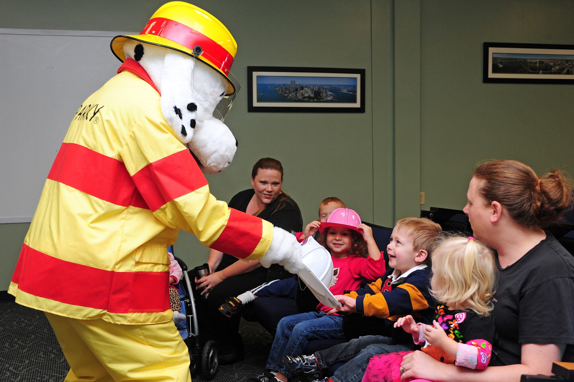 Sparky, 4th Civil Engineer Squadron fire prevention mascot, hands out helmets to children from the child development center during a Fire Prevention Week tour at Seymour Johnson Air Force Base, N.C., Oct. 9, 2013. Kitchen fire prevention is the theme of this year’s events. Fire Prevention Week runs from Oct. 7 – 11. (U.S. Air Force photo by Airman 1st Class John Nieves Camacho)