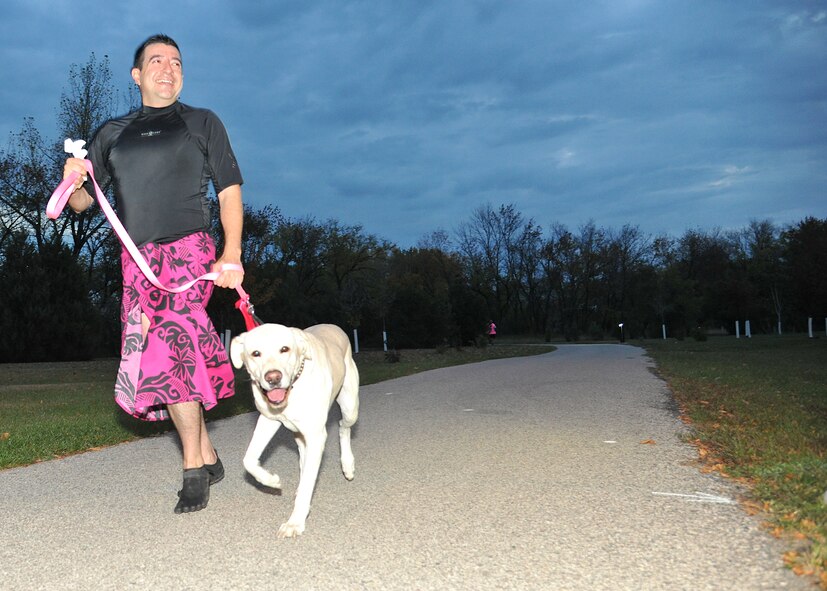 Chaplain (Capt.) Ruben Covos from the 319th Air Base Wing, runs with his Labrador retriever, Ramon, during the Breast Cancer Awareness 5K while wearing a hand printed pink, Tahitian pareo, Oct. 10, 2013. The 319th Medical Group at Grand Forks Air Force Base, N.D., hosted the event and asked 5K runner, walkers, and joggers to wear pink during the event in order to show support for the worthy cause. (U.S. Air Force photo/Senior Airman Xavier Navarro)