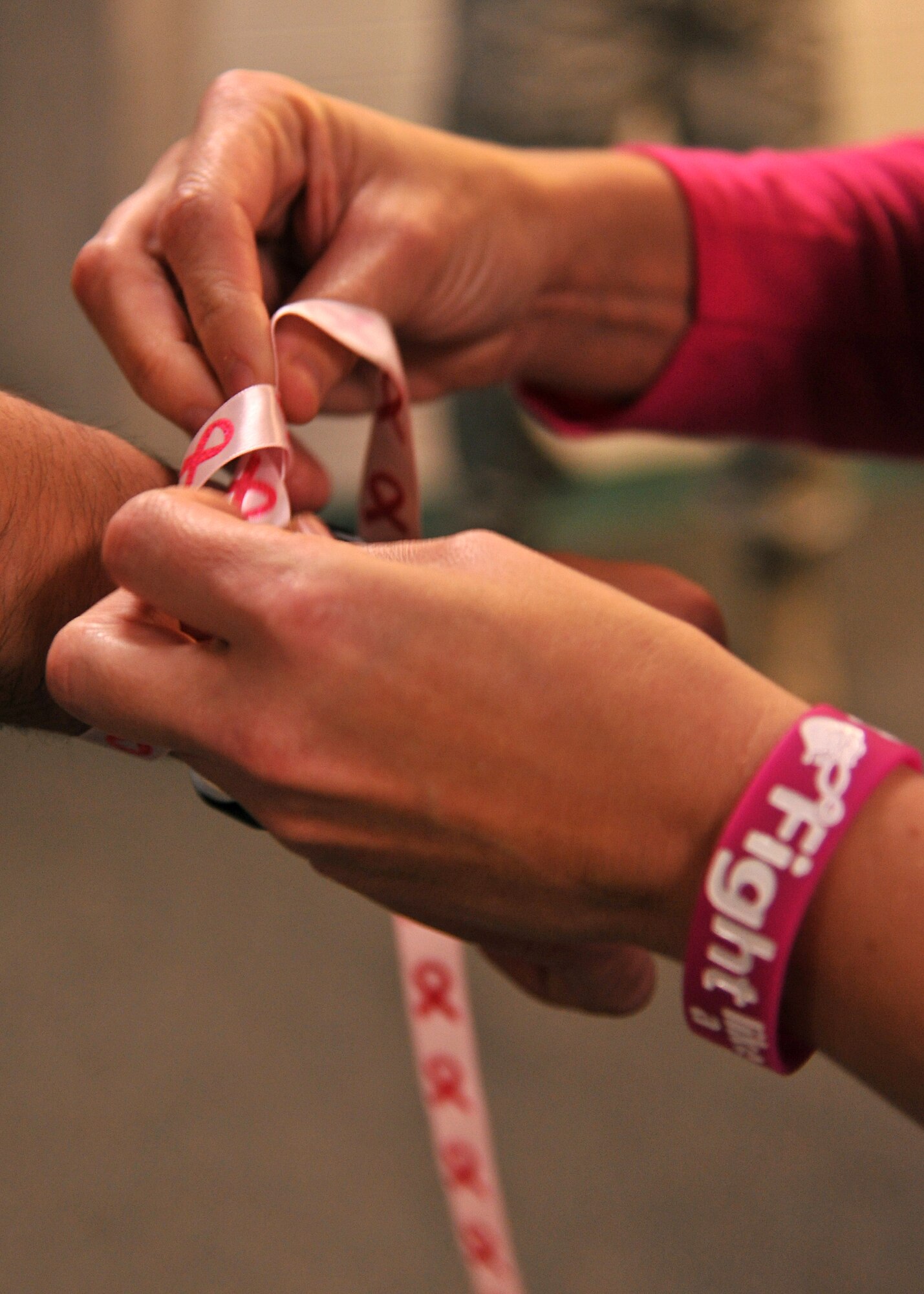 Participants make bracelets out of pink ribbons during the opening remarks at the base fitness center Oct. 10, 2013. Several participants wore pink ribbons on their wrists in observance of Breast Cancer Awareness Month during a BCA Month 5K hosted by the 319th Medical Group at Grand Forks Air Force Base, N.D. (U.S. Air Force photo/Senior Airman Xavier Navarro)