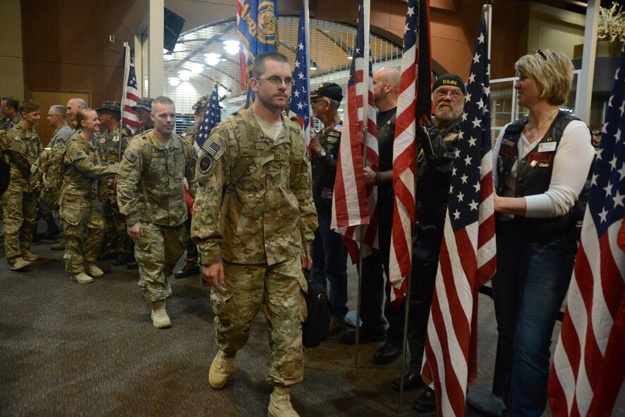 Senior Airman Christopher Mann leads a group of 119th Security Forces Squadron, North Dakota Air National Guard, members including Tech. Sgt. Ryan Bruggeman, Staff Sgt. Kelli Eidem and Staff Sgt. Lacey Bunkelman, as they walk through a greeting line of North Dakota National Guard leaders and Patriot Guard volunteers upon their Oct. 8, 2013, homecoming to Hector International Airport, Fargo, N.D., after completing a six-month deployment to Afghanistan. (U.S. Air National Guard photo by SMSgt. David H. Lipp/Released)