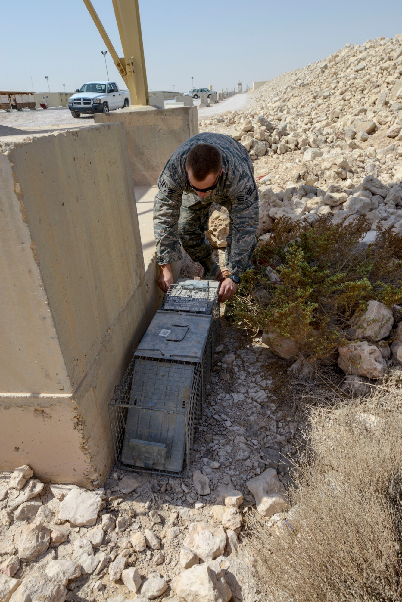 Senior Airman Jordan Hocker prepares a live trap beside a concrete wall at the 379th Air Expeditionary Wing in Southwest Asia, Oct. 8, 2013. Pest management Airmen is responsible for removing or relocating wildlife on the installation. Hocker is a 379th ECES pest management journeyman deployed from Ramstein Air Base, Germany, and hails from Indianapolis. (U.S. Air Force photo/Tech. Sgt. Joselito Aribuabo)