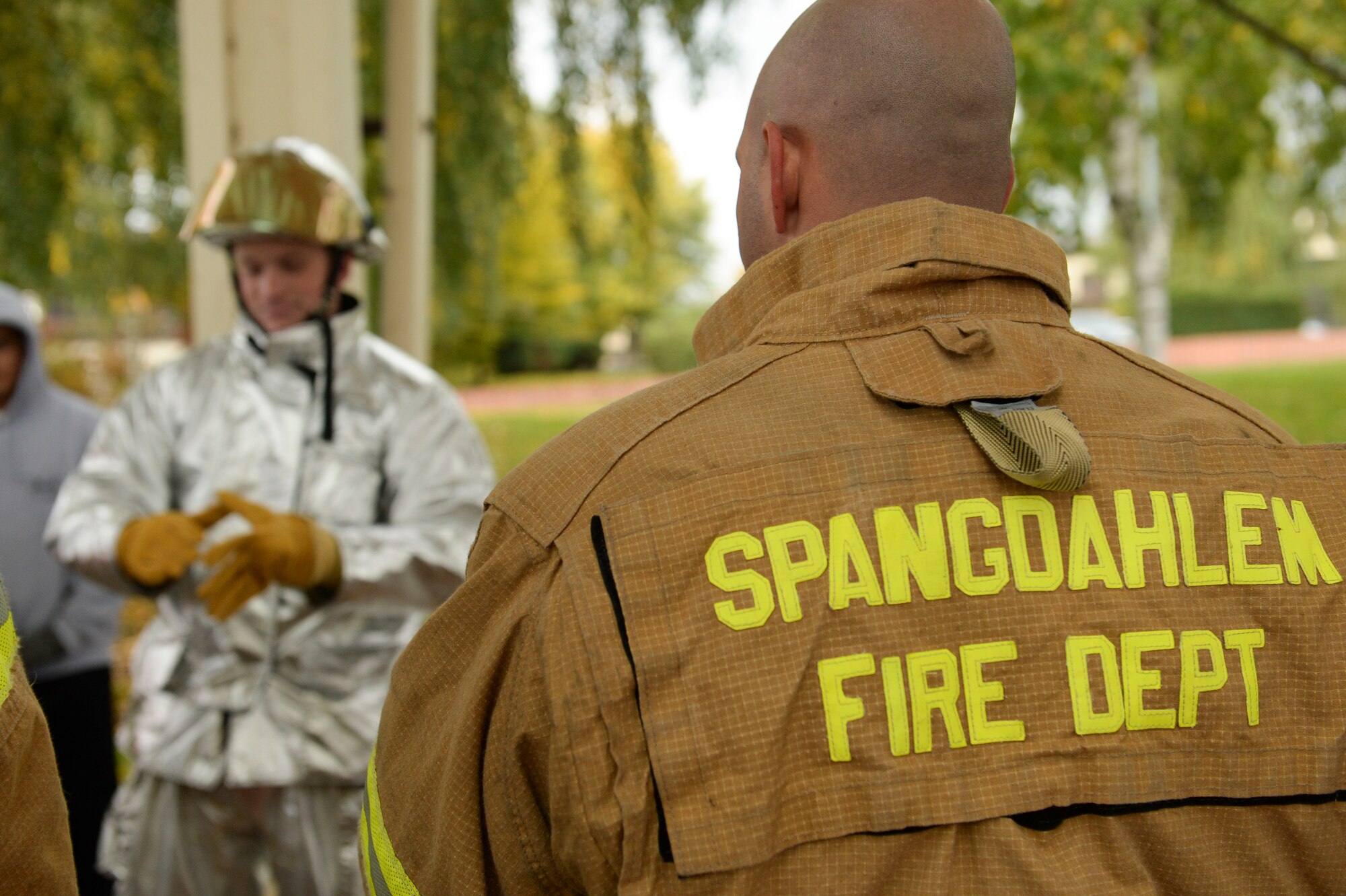 SPANGDAHLEM AIR BASE, Germany--A member of the 52nd Civil Engineer Squadron fire departmen right, gives instruction on how to put on fire fighter gear  to participants prior to the start of the Fire Muster competition Oct. 10, 2013. The Fire Muster is a timed competition where teams from Saber Nation simulate the experience of fighting a fire. (U.S. Air Force photo by Senior Airman Rusty Frank/Released)