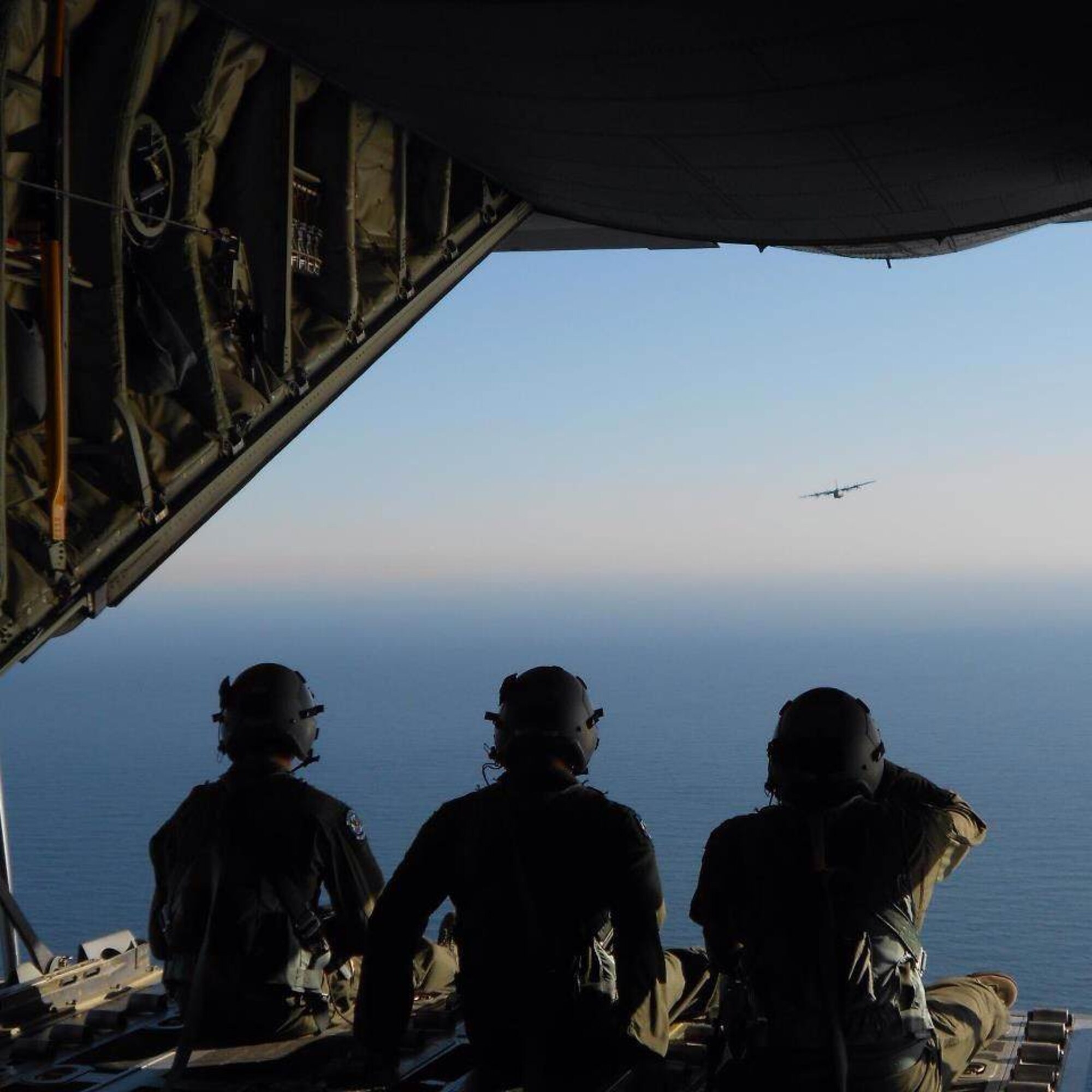 (From left to right), Staff Sgt. Matthew Merkley, Senior Airman Nicholas Cunningham, and Staff Sgt. Michael Demik, 37th Airlift Squadron loadmaster, looks out of the back of a C-130J Super Hercules during a training mission, Feb. 2012. (Courtesy photo)