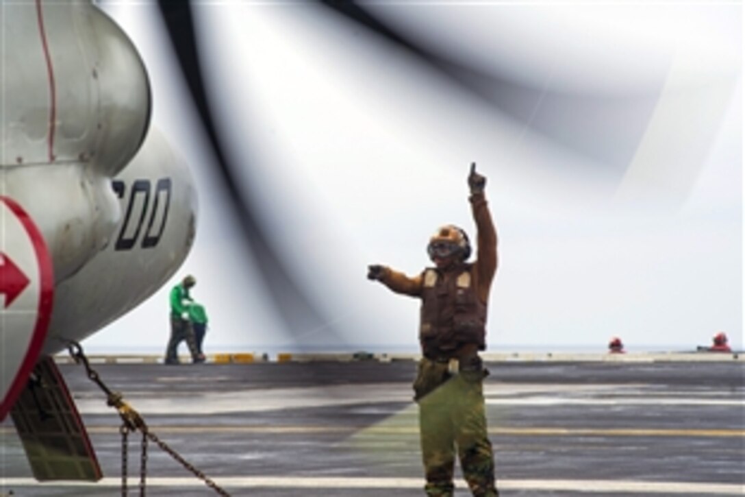 U.S. Navy Airman Calvin Jenkins signals an E-2C Hawkeye crew during engine start-up on the flight deck of the aircraft carrier USS George Washington in the waters to the west of the Korean Peninsula, Oct. 10, 2013. 