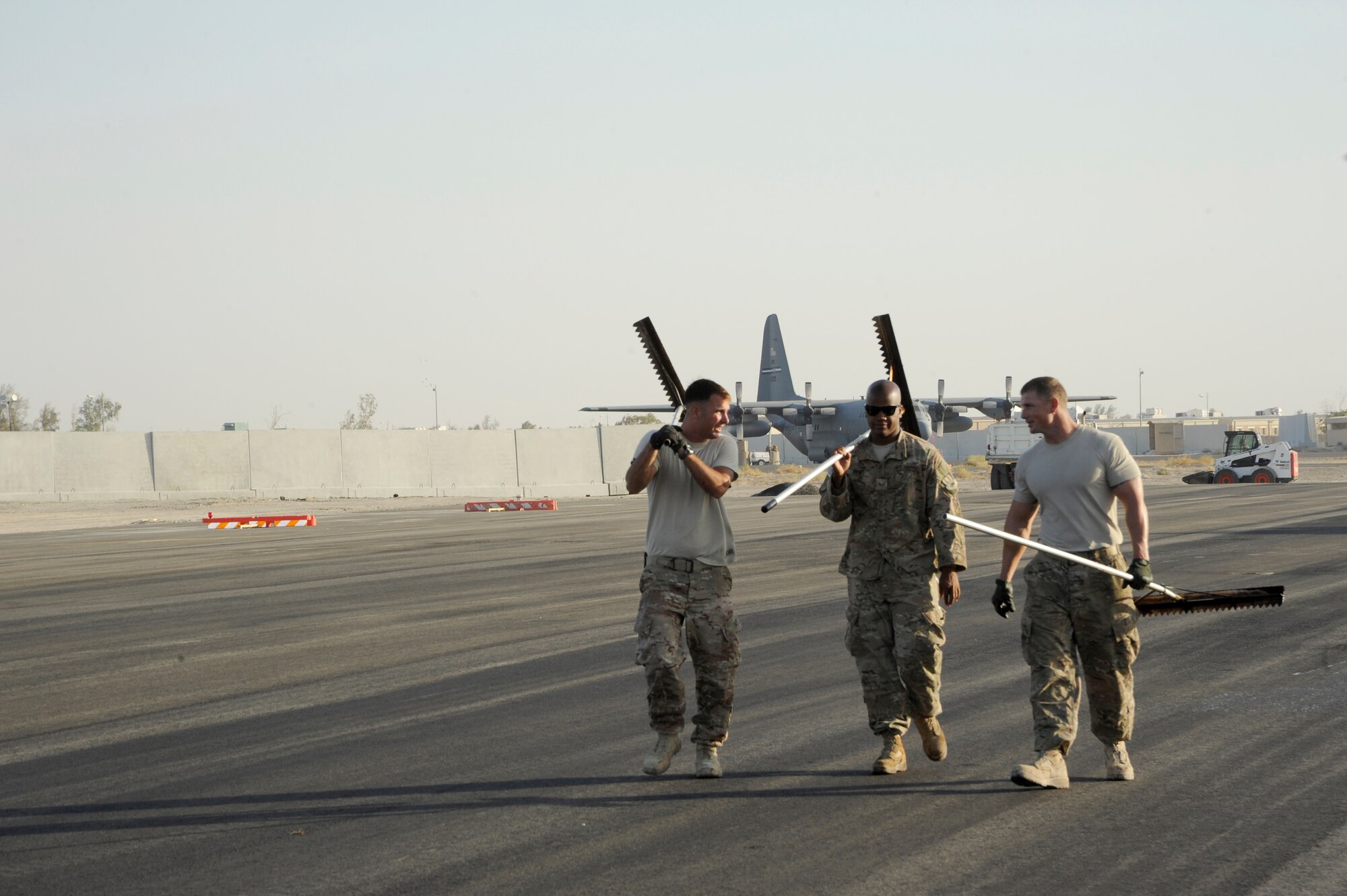 From left to right, Staff Sgt. Christopher D’Angelo, 557th Expeditionary Red Horse Squadron, Senior Airman James Dowdy, 557th Expeditionary Red Horse Squadron, and Staff Sgt. Thomas Ledbetter, 557th Expeditionary Prime Beef Squadron, all are heavy equipment operators, walk back to the next area of work here, Oct. 4, 2013.  They are part of the team that levels the freshly laid asphalt before a roller compacts it. D’Angelo, a native of Philadelphia, Pa., is deployed out of Malmstrom Air Force Base, Mont. Dowdy, a native of Columbia, S.C., is deployed out of Malmstrom Air Force Base. Ledbetter, a native of Opelika, Ala., is deployed out of Barksdale Air Force Base, La. (U.S. Air Force photo by Master Sgt. Christopher A. Campbell)