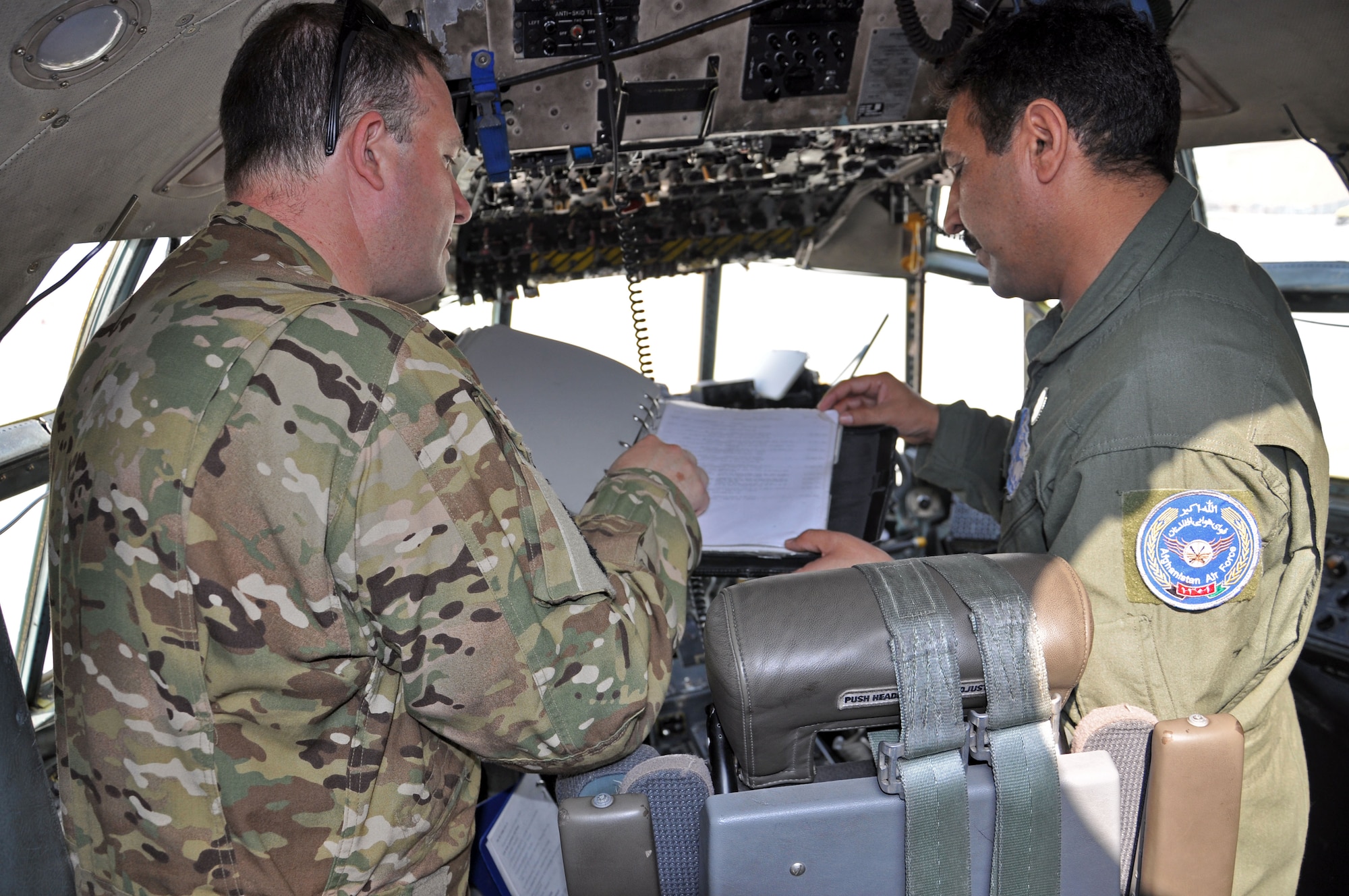 Afghan Air Force Col. Almal Pacha, one of two AAF C-130 pilots, and Maj. Chris Garcia, 538th Air Expeditionary Advisory Squadron C-130 pilot and advisor, go over flight plans prior to the first operational AAF C-130 mission Oct. 10, 2013 at Kabul International Airport, Afghanistan. The flight was not only the first operational mission for the new C-130s, but also the first upgrade training for Pacha and 1st Lt. Khial Shinwari, the first two AAF C-130 pilots. The training focused on the basics of transporting passengers and cargo from one point to another as well as instrument flying. (U.S. Air Force photo/Capt. Anastasia Wasem)
